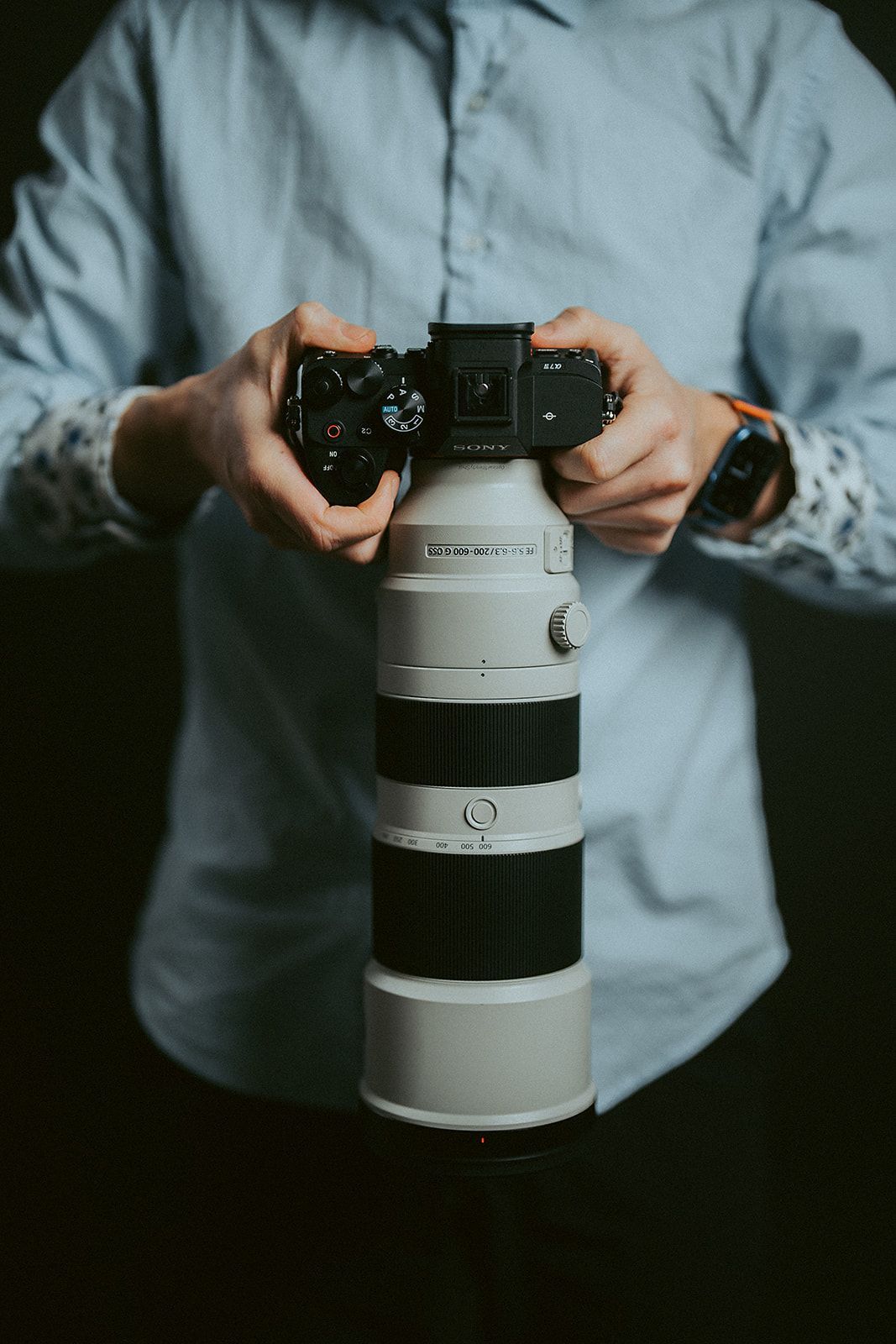 A man is holding a camera and a lens in his hands.