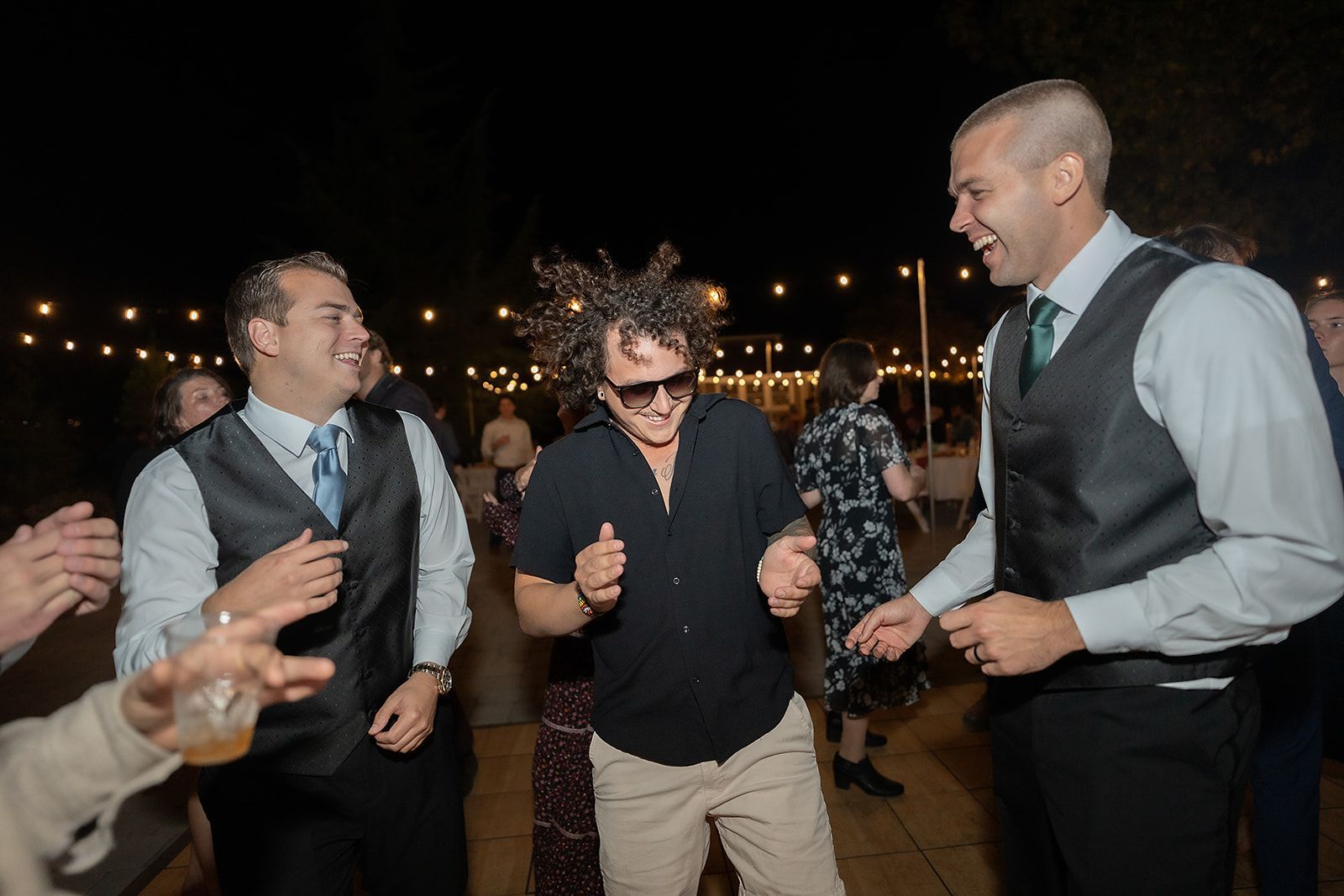 A group of men are dancing at a wedding reception.