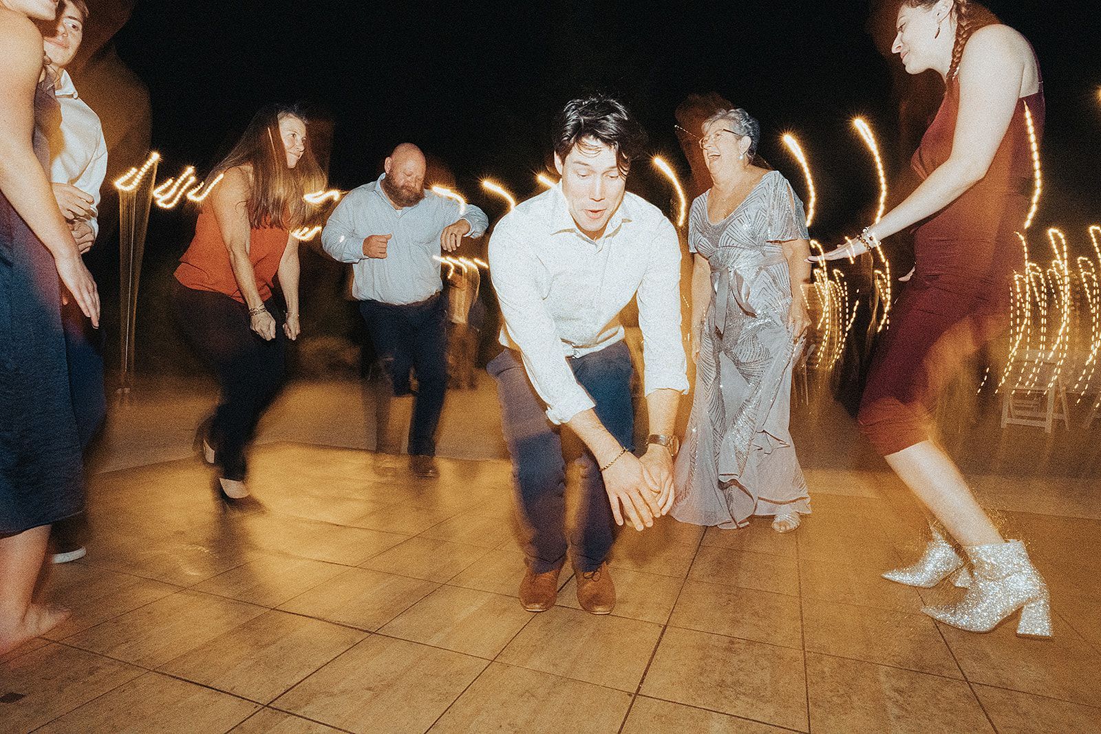 A group of people are dancing on a dance floor at a wedding reception.
