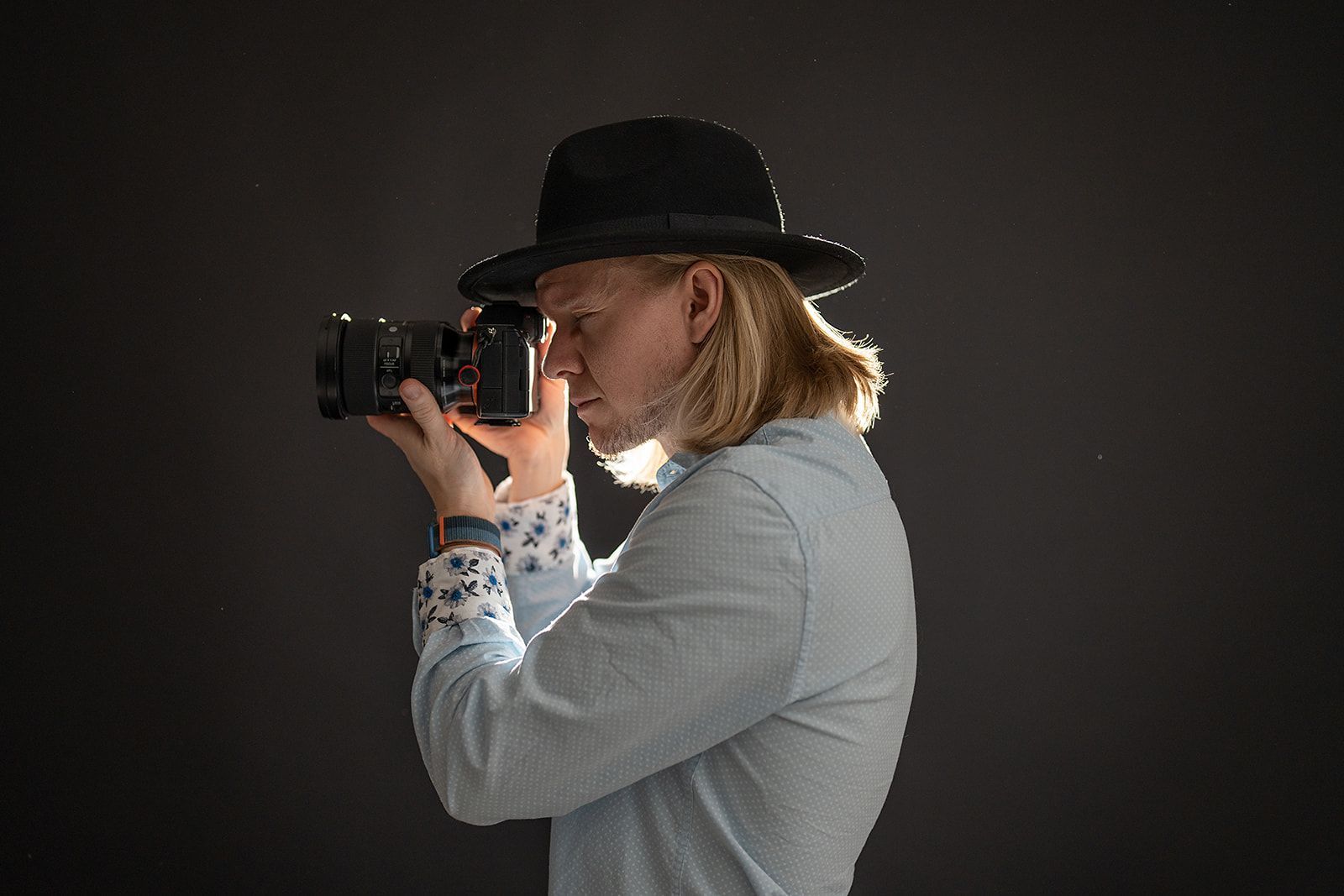 A man in a hat is taking a picture with a camera.