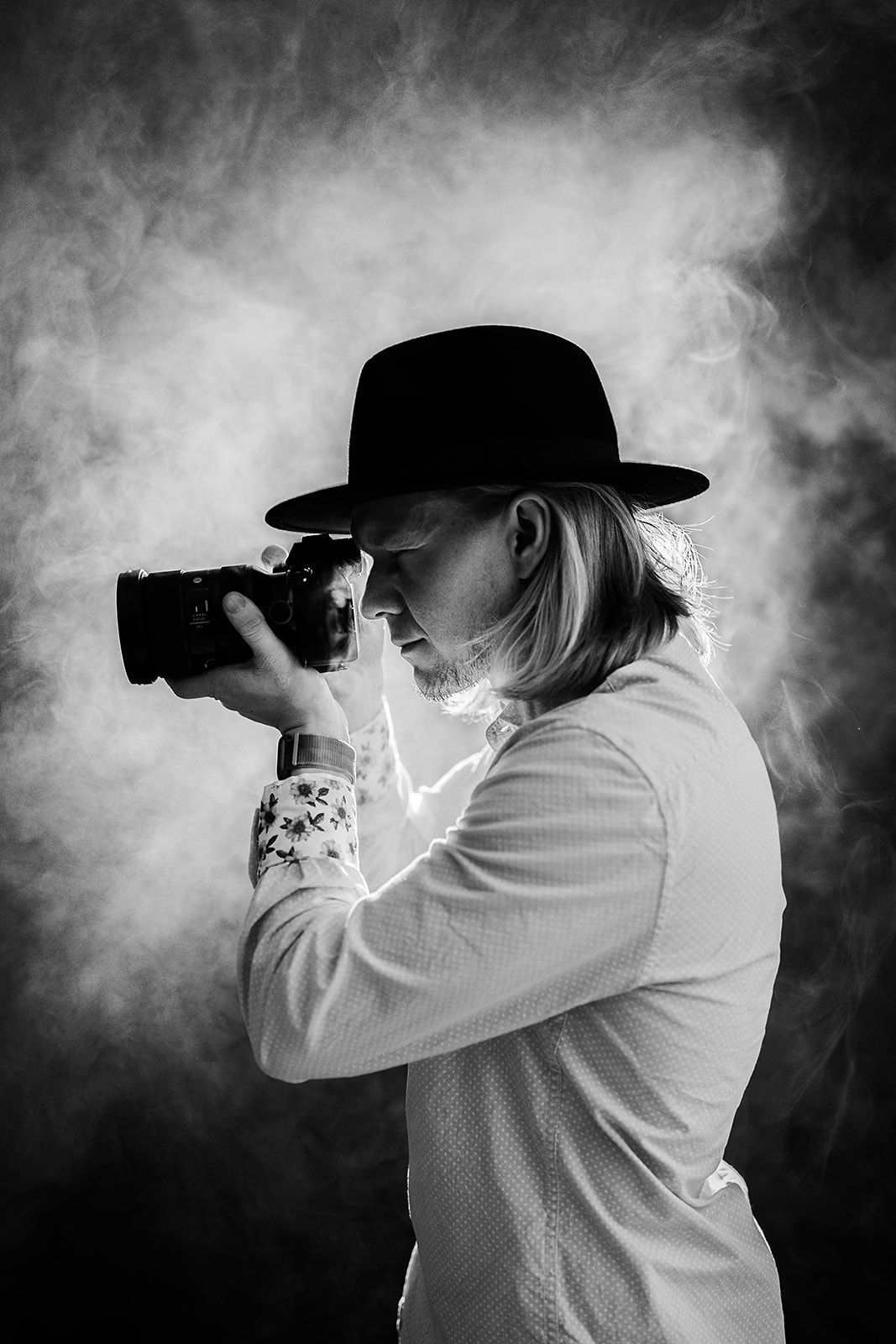 A man in a hat is taking a picture with a camera.