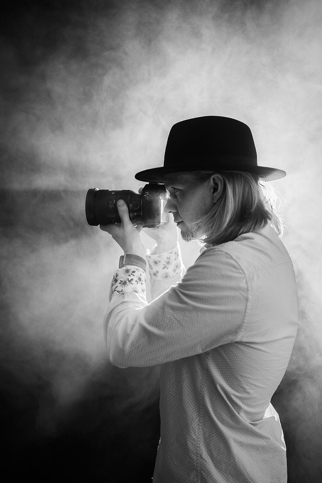 A man in a hat is taking a picture with a camera.