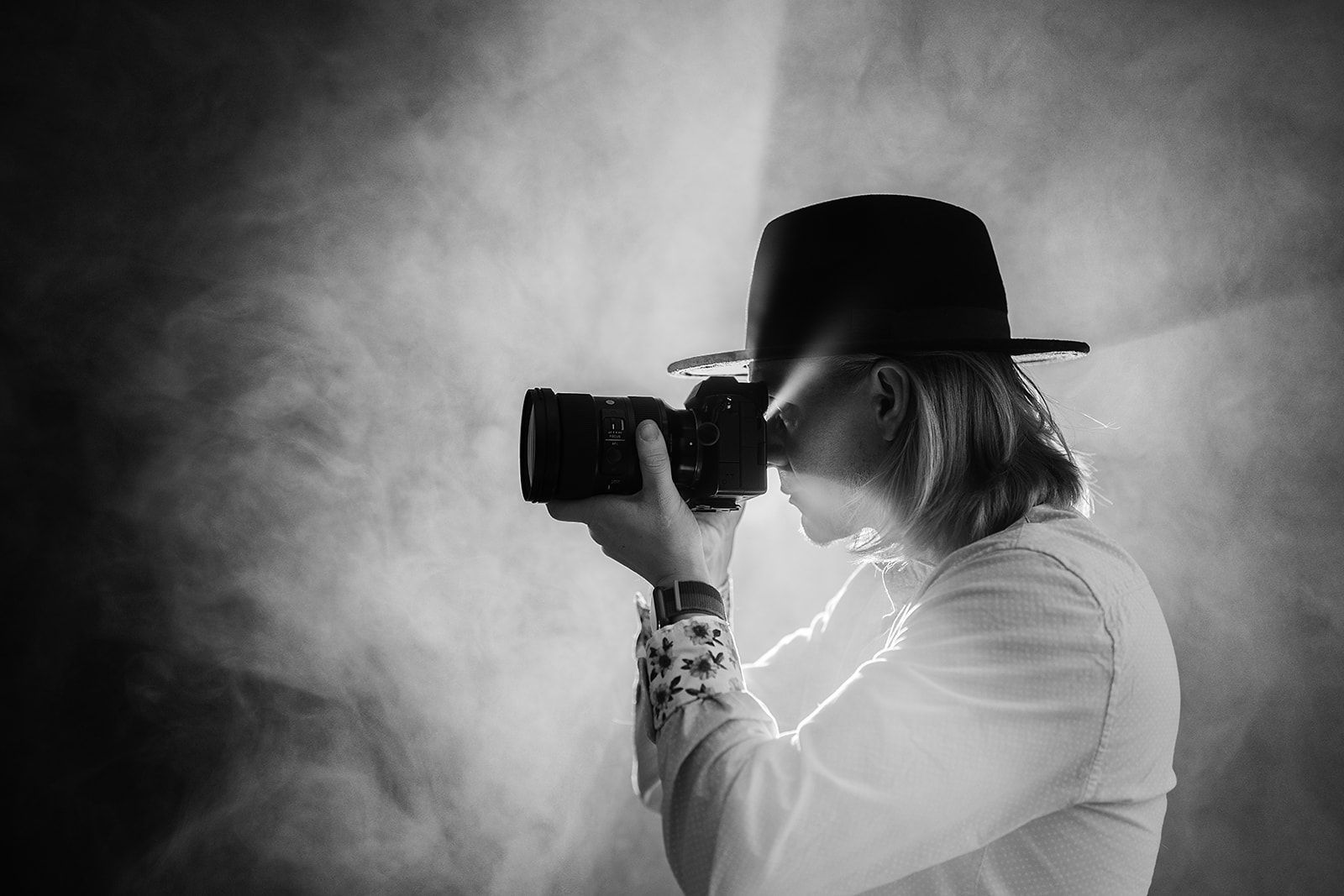 A man in a hat is taking a picture with a camera.