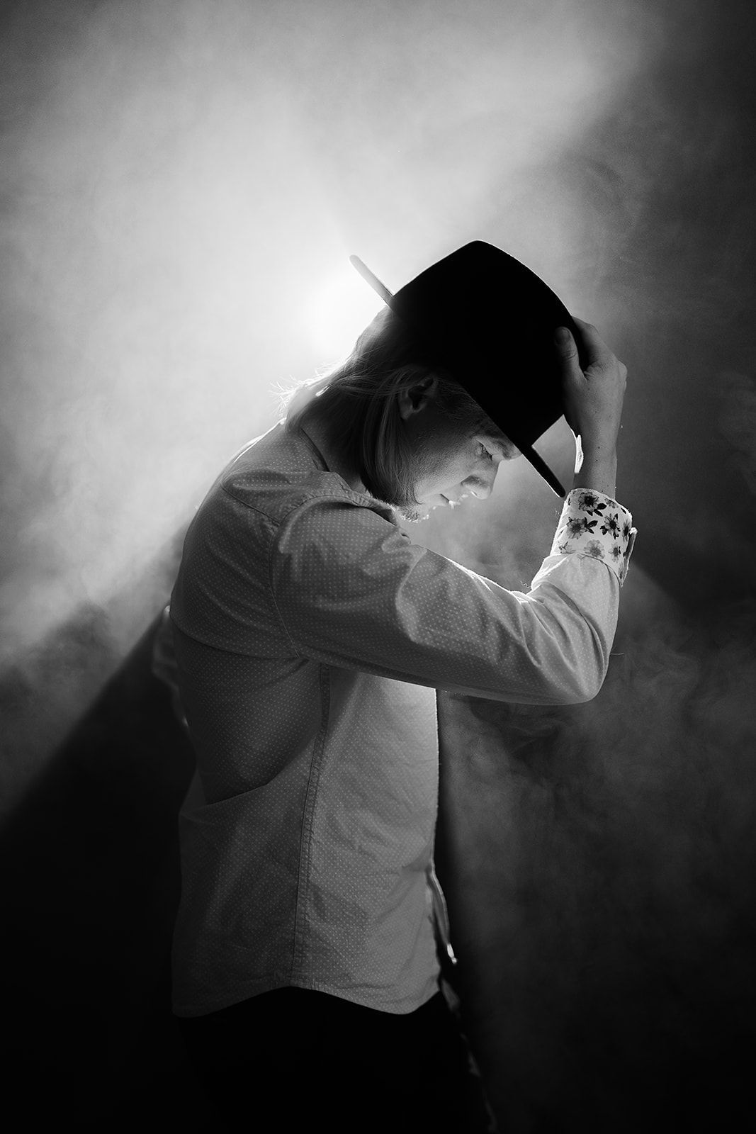 A man is covering his face with his hands in a black and white photo.