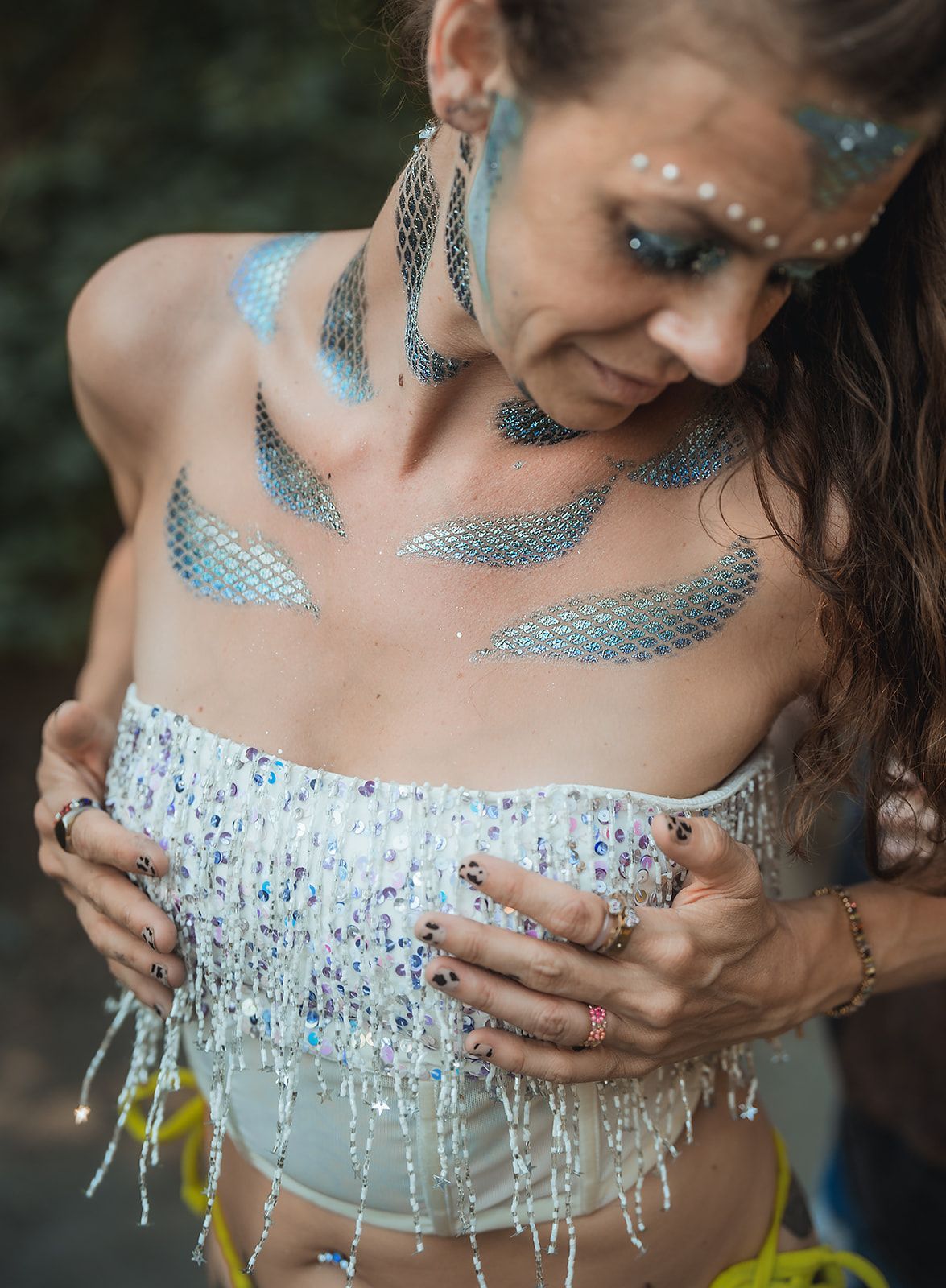 A woman wearing a white top with feathers painted on her chest.
