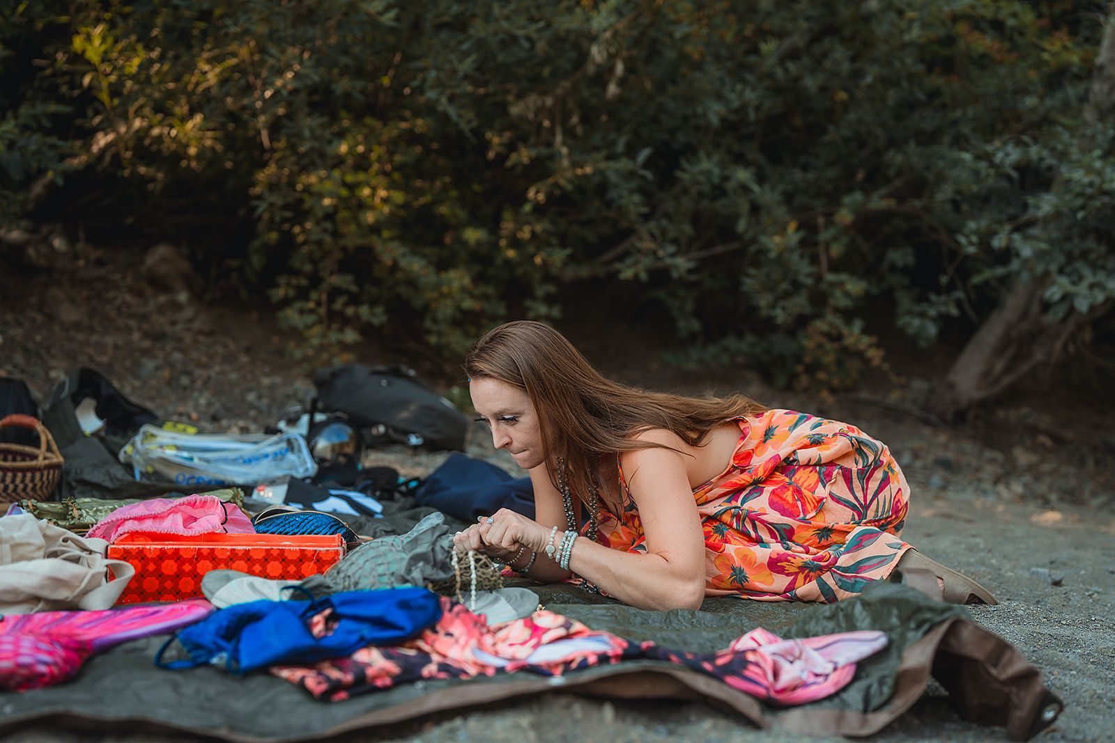 A woman is laying on a blanket in the woods.