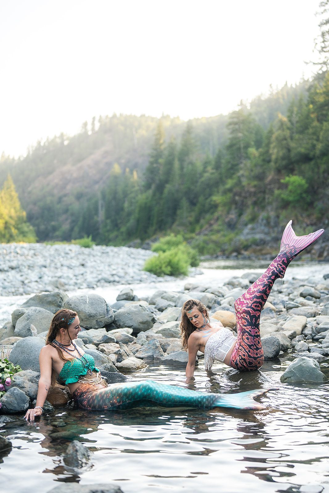 Two mermaids are swimming in a river.