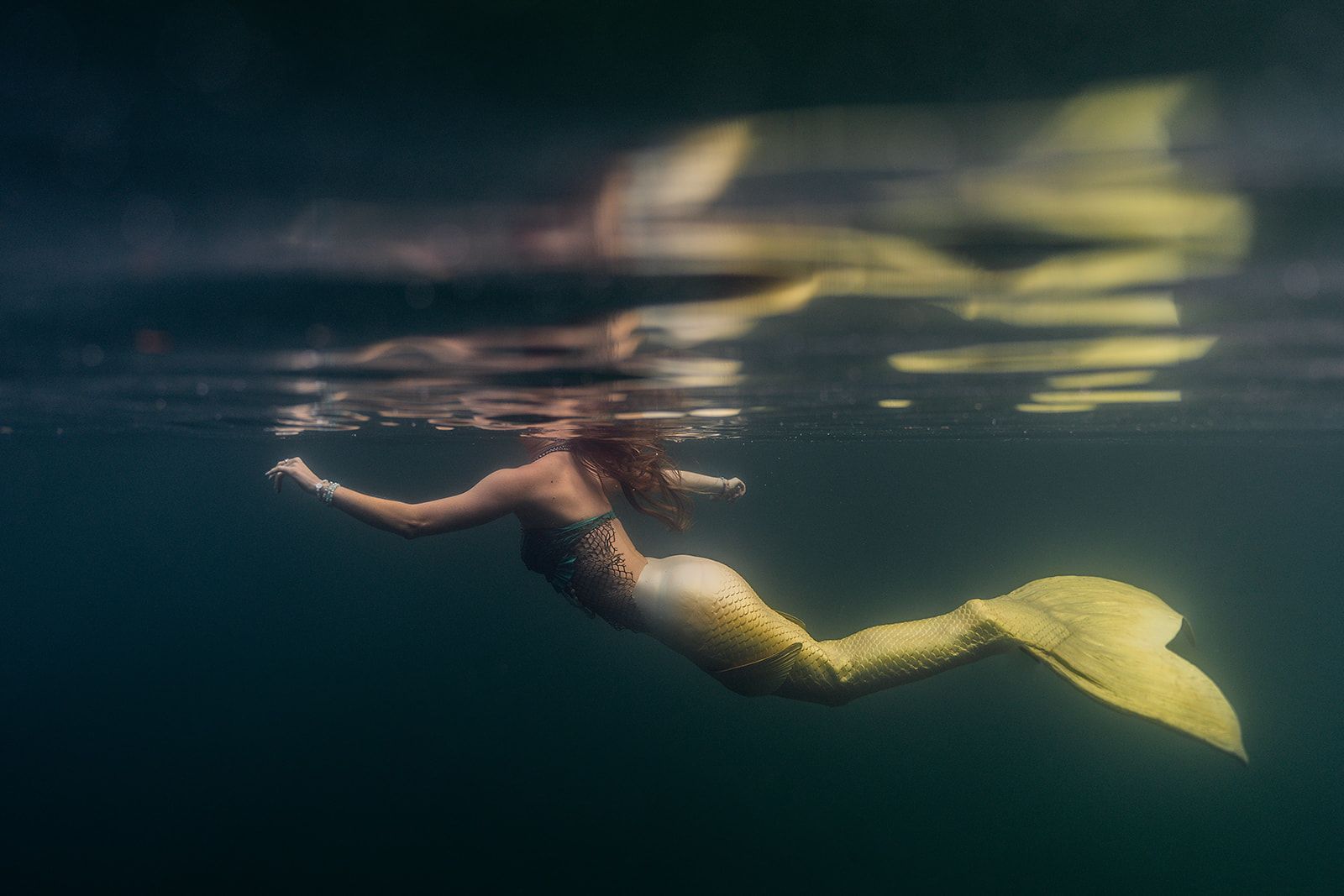A mermaid is swimming underwater in the ocean.