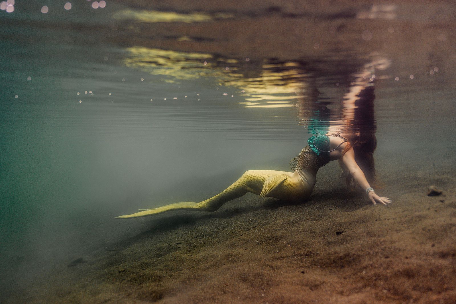 A woman in a mermaid costume is swimming underwater.