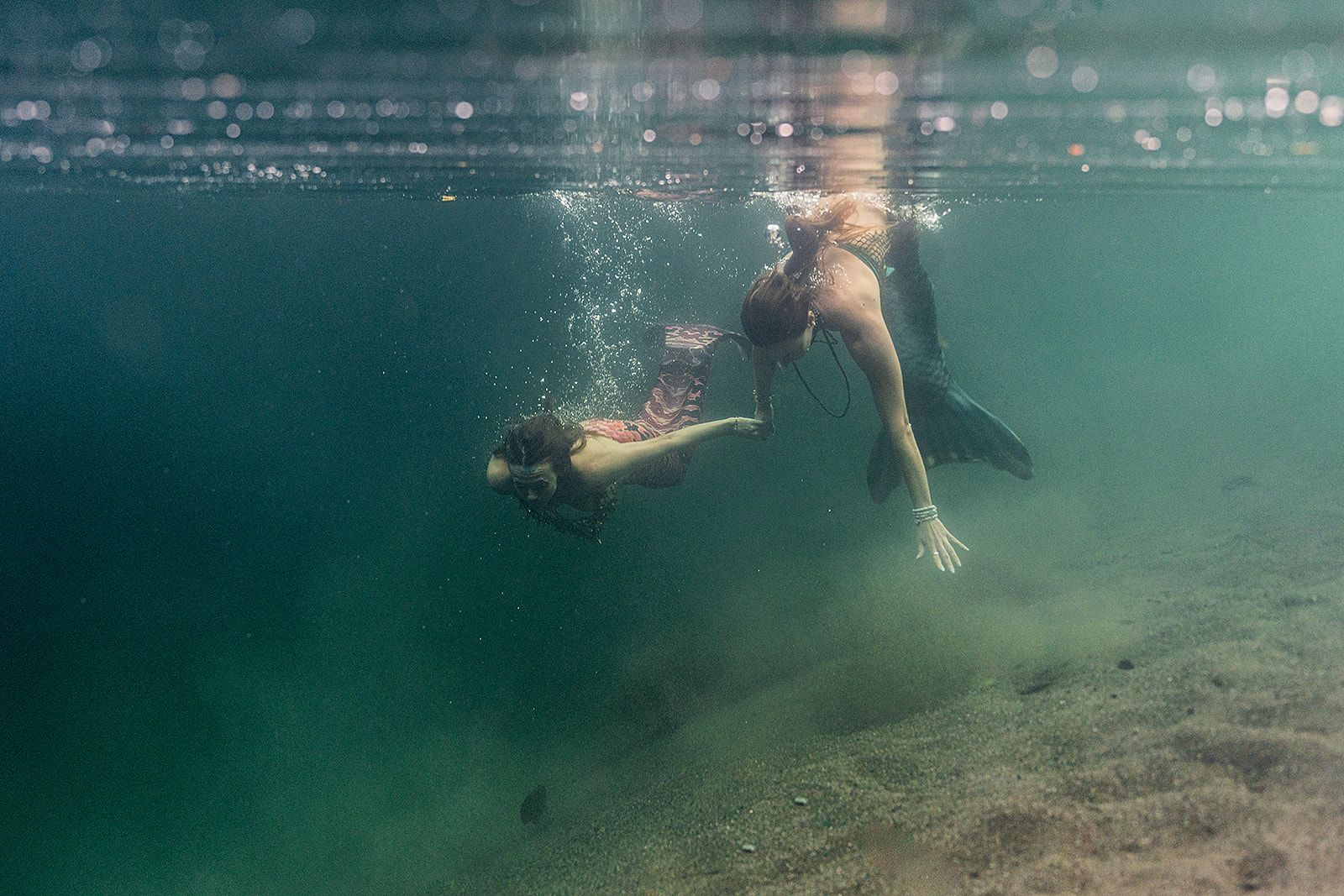 Two women are swimming underwater in the ocean.