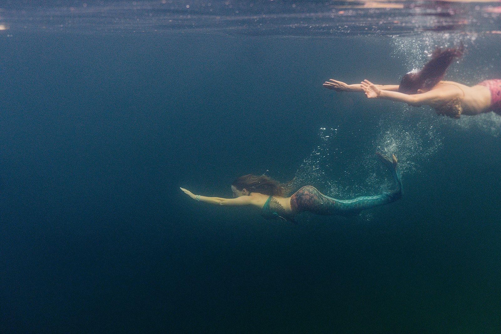 A man and a woman are swimming underwater in the ocean.