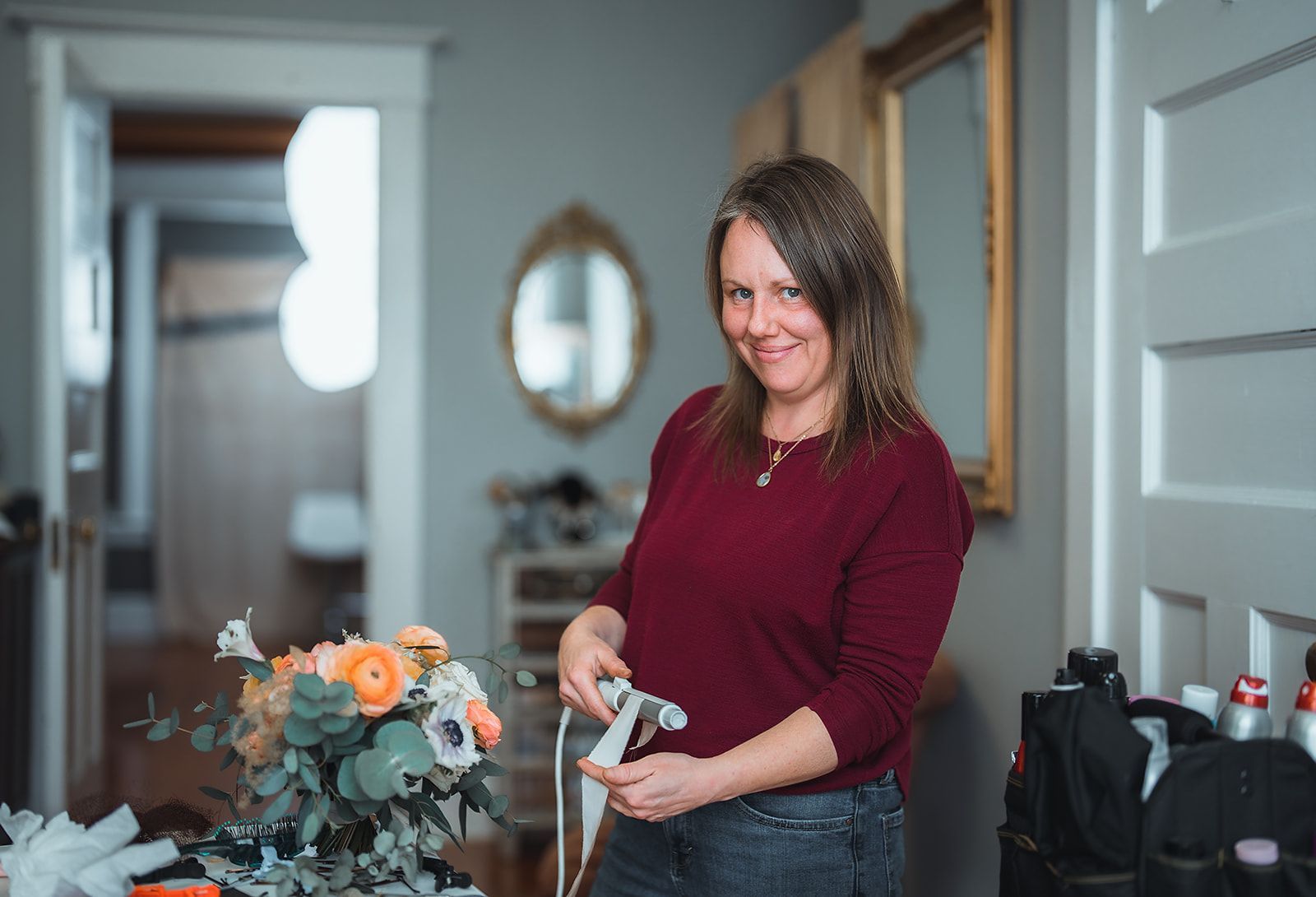 A woman is standing in front of a vase of flowers in a living room.