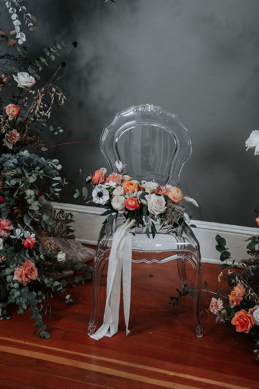 A clear chair with flowers on it is sitting on a wooden floor.