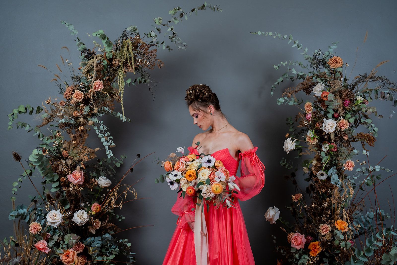 A woman in a red dress is holding a bouquet of flowers.