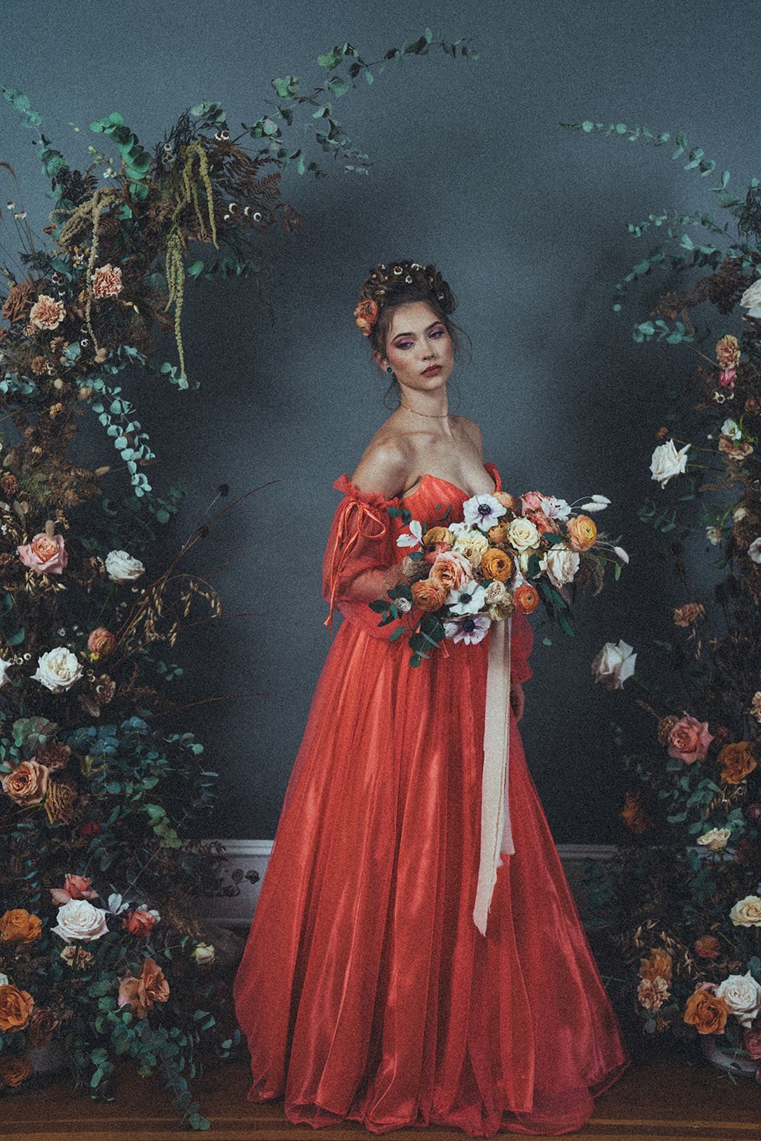 A woman in a red dress is holding a bouquet of flowers.