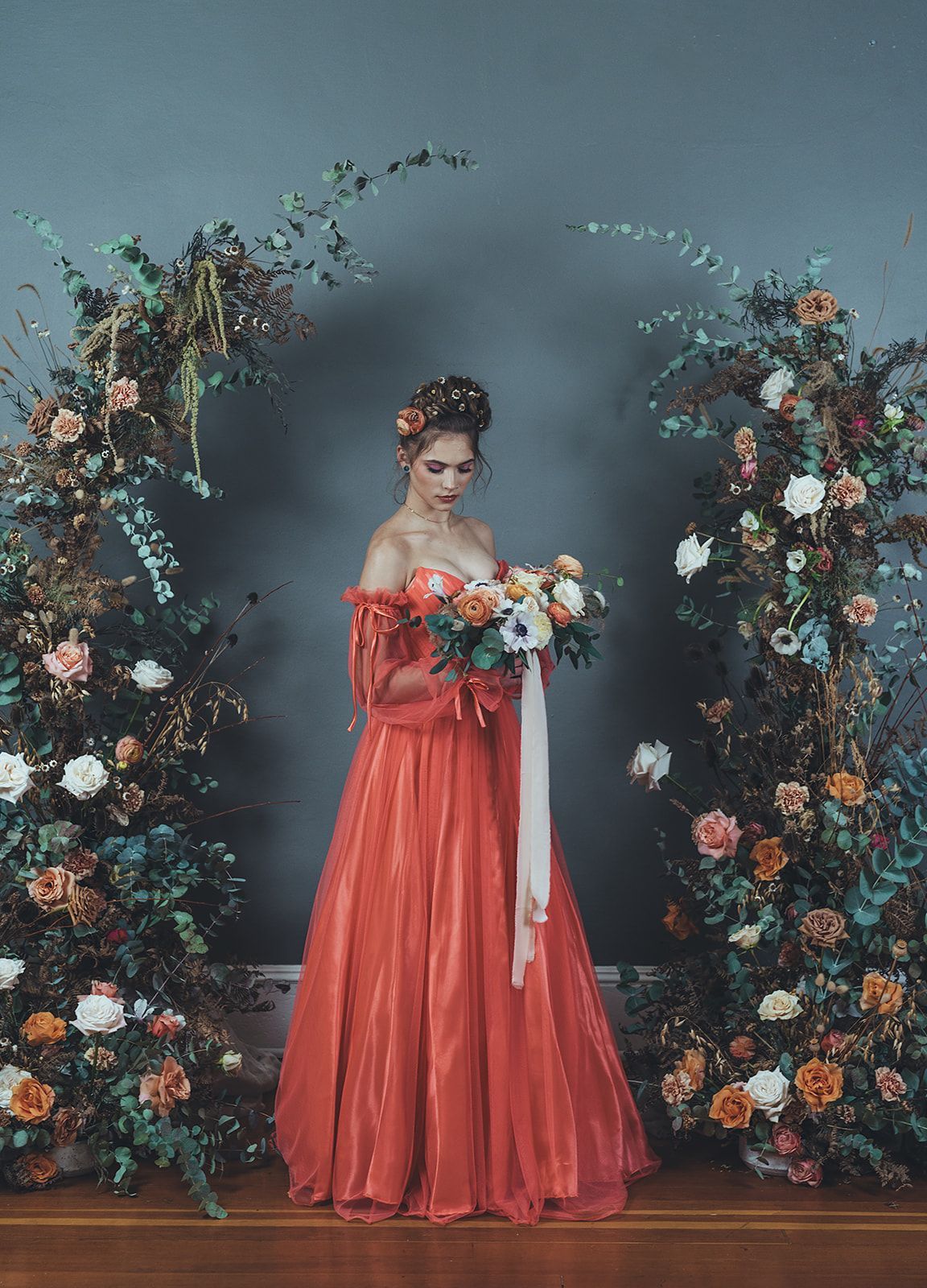 A woman in a red dress is holding a bouquet of flowers.