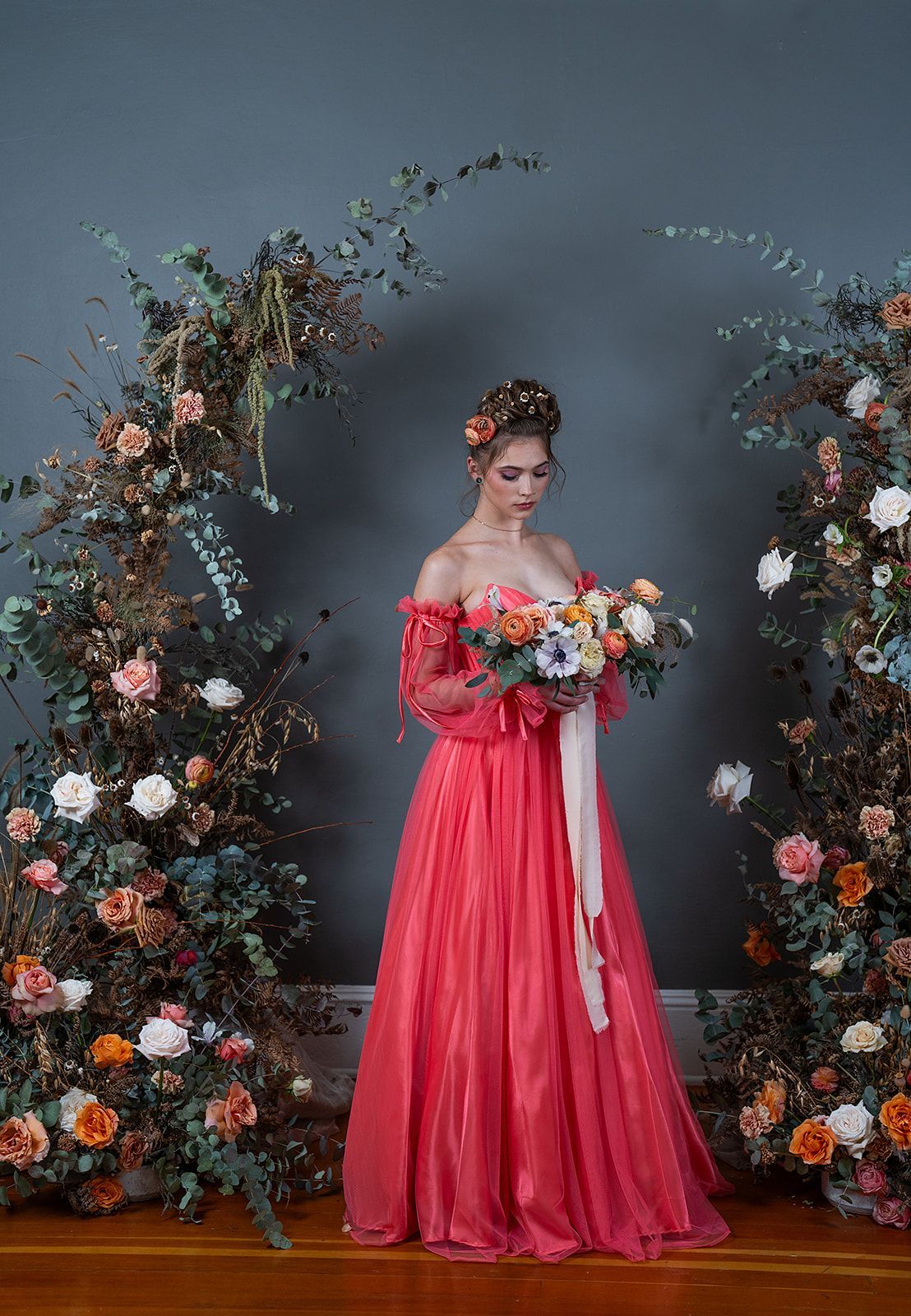 A woman in a red dress is holding a bouquet of flowers.