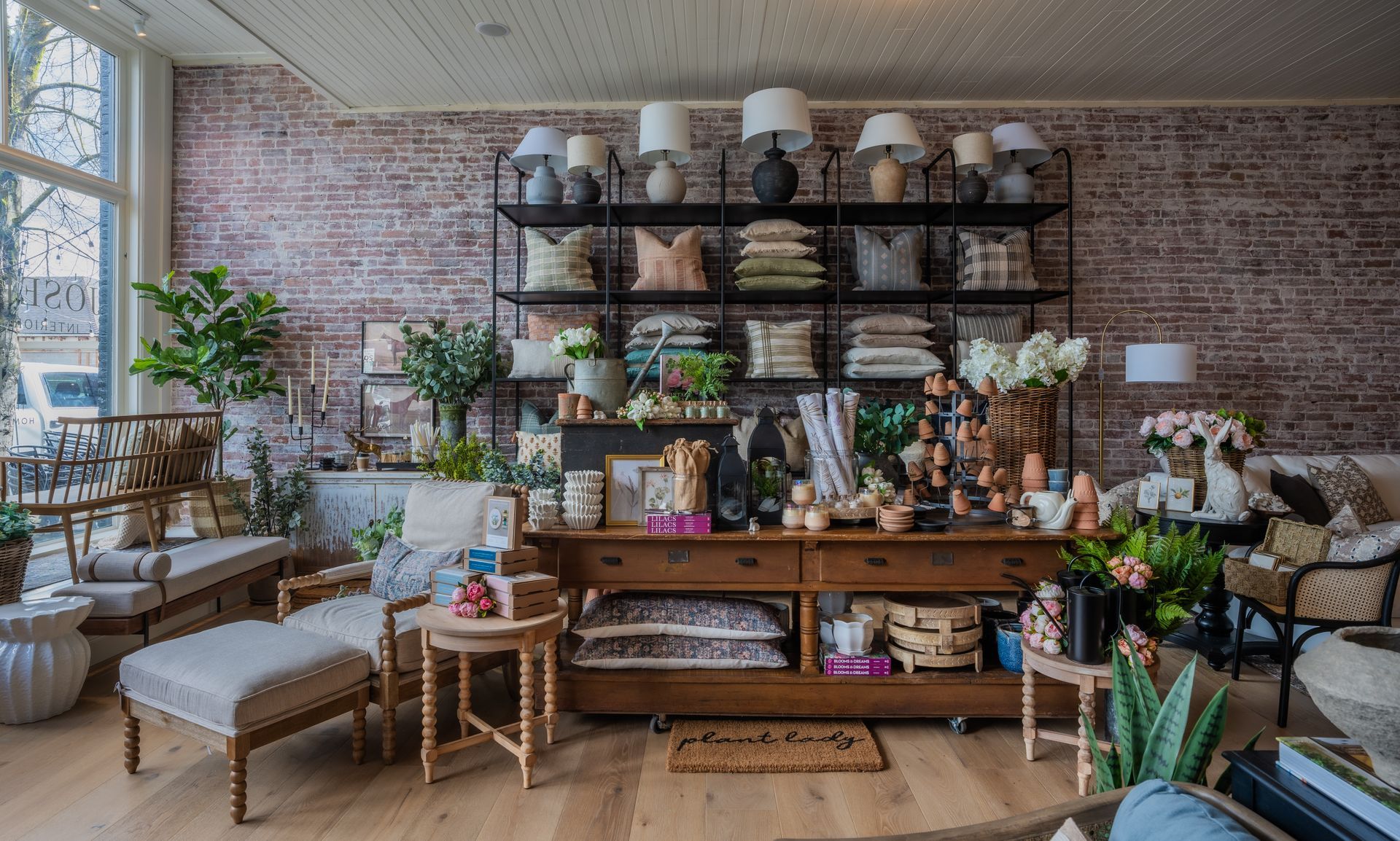 A living room filled with furniture and plants and a brick wall.