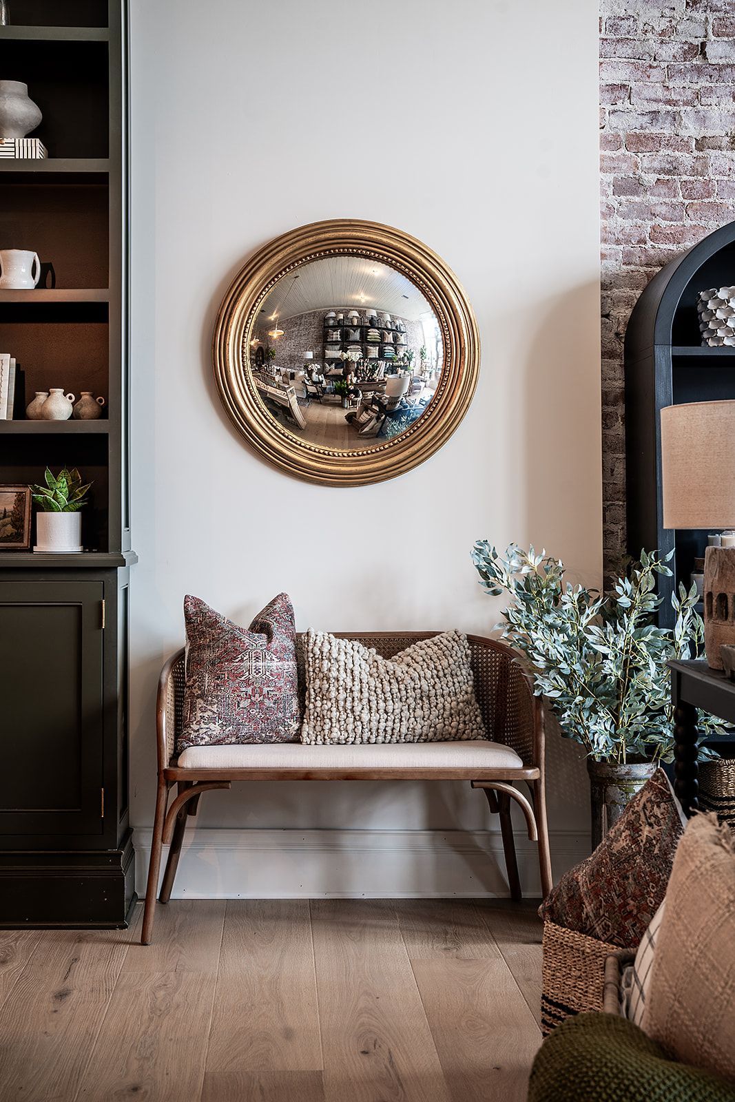 A living room with a bench and a mirror on the wall.