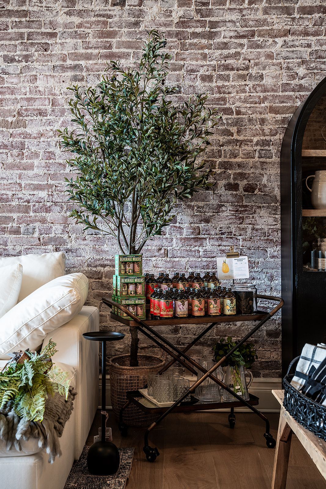 A living room with a brick wall and a bar cart with jars on it.