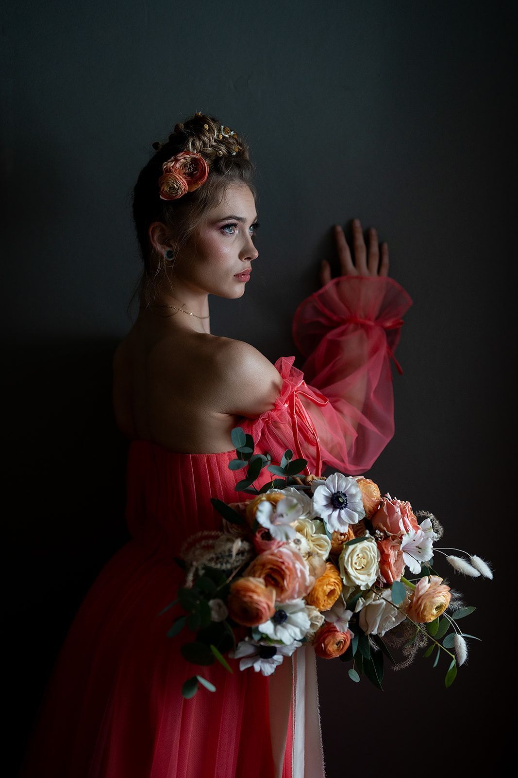A woman in a red dress is holding a bouquet of flowers.