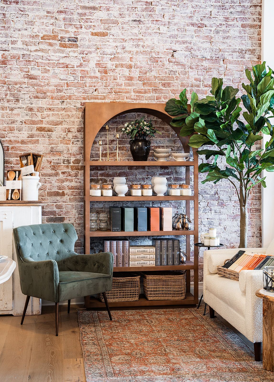 A living room with a brick wall , chair , couch and bookshelf.
