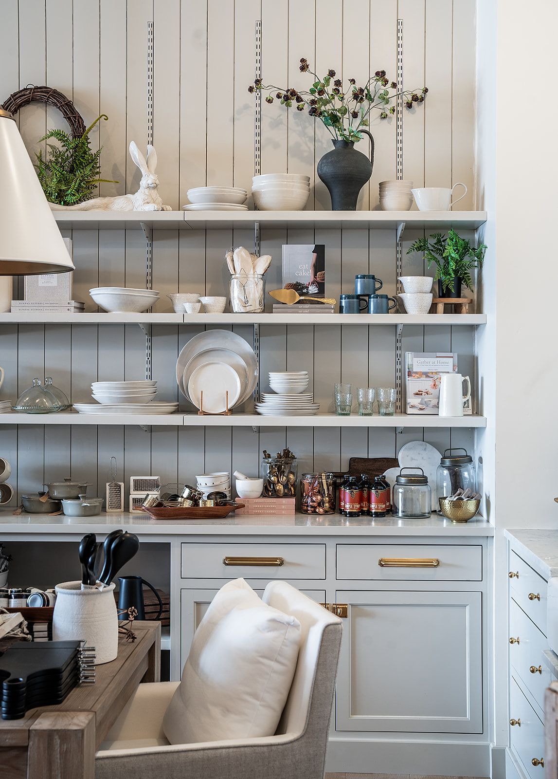 A kitchen with white cabinets and shelves filled with dishes and utensils.