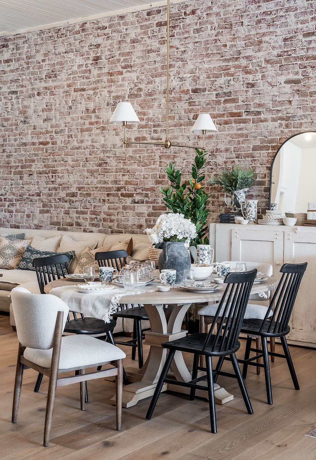 A dining room with a table and chairs and a brick wall.
