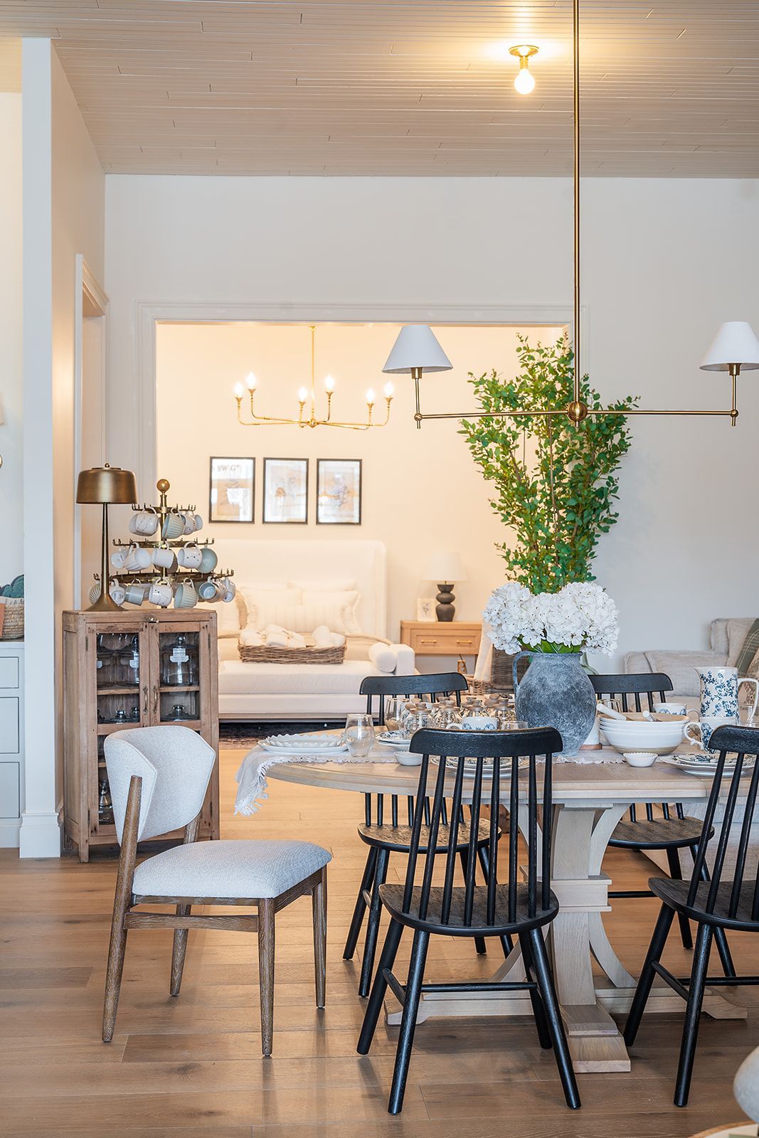 A dining room with a table and chairs and a living room in the background.