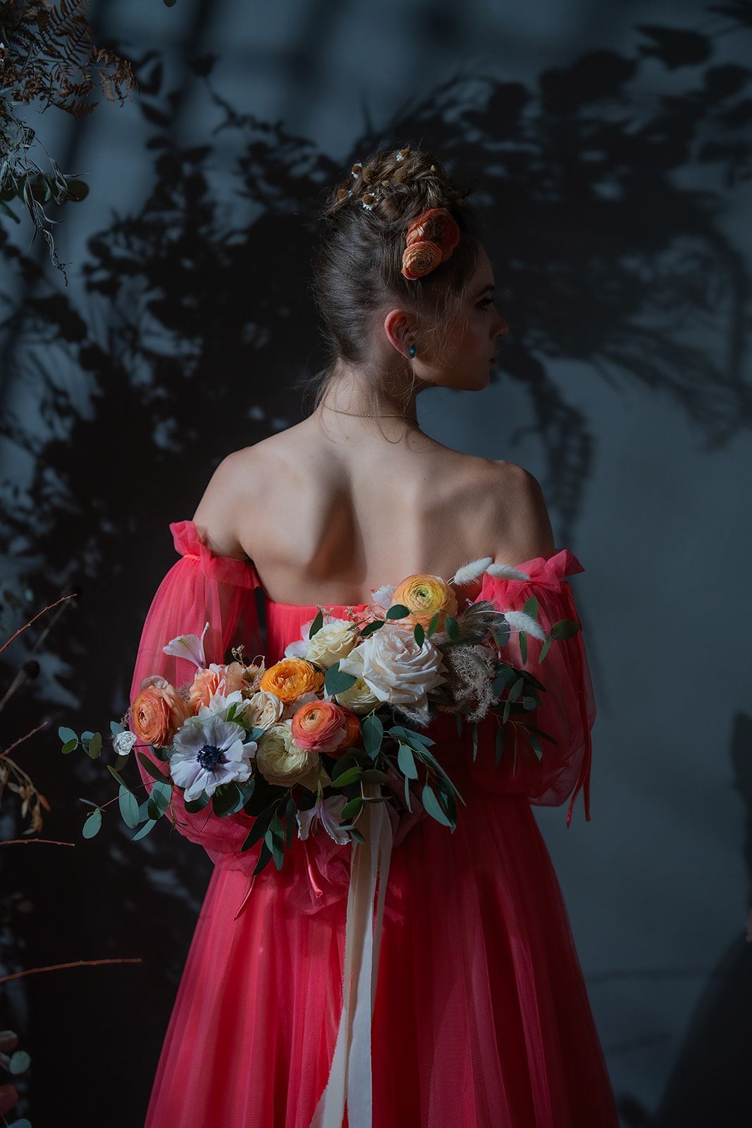 A woman in a red dress is holding a bouquet of flowers.
