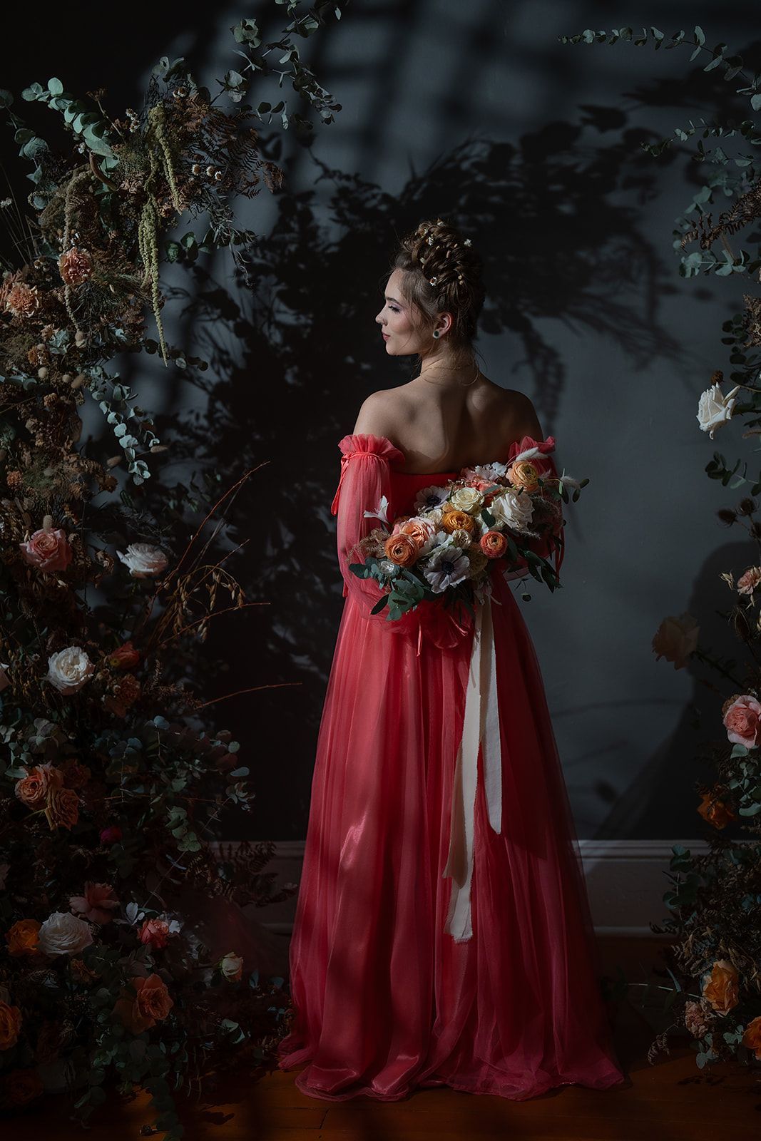 A woman in a red dress is holding a bouquet of flowers.