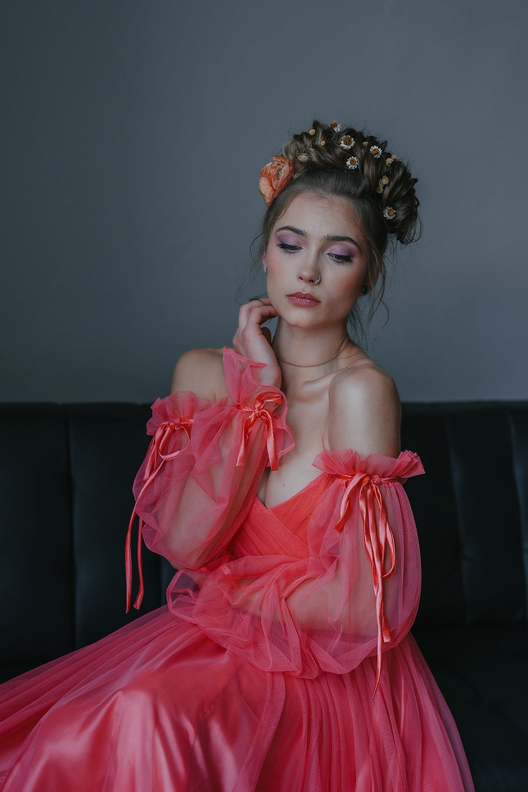 A woman in a red dress is sitting on a couch.