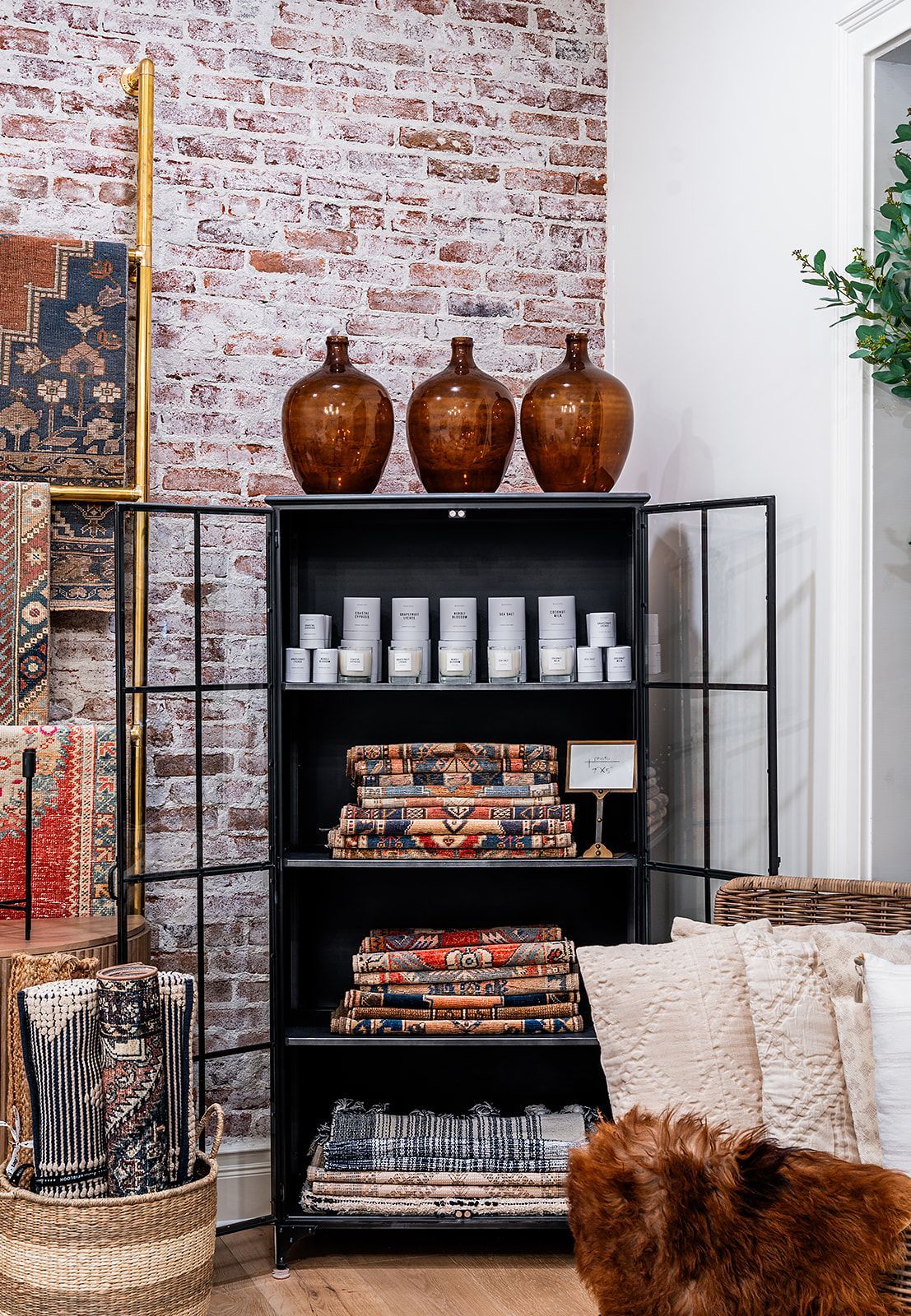 A living room with a brick wall and a shelf with vases on it.