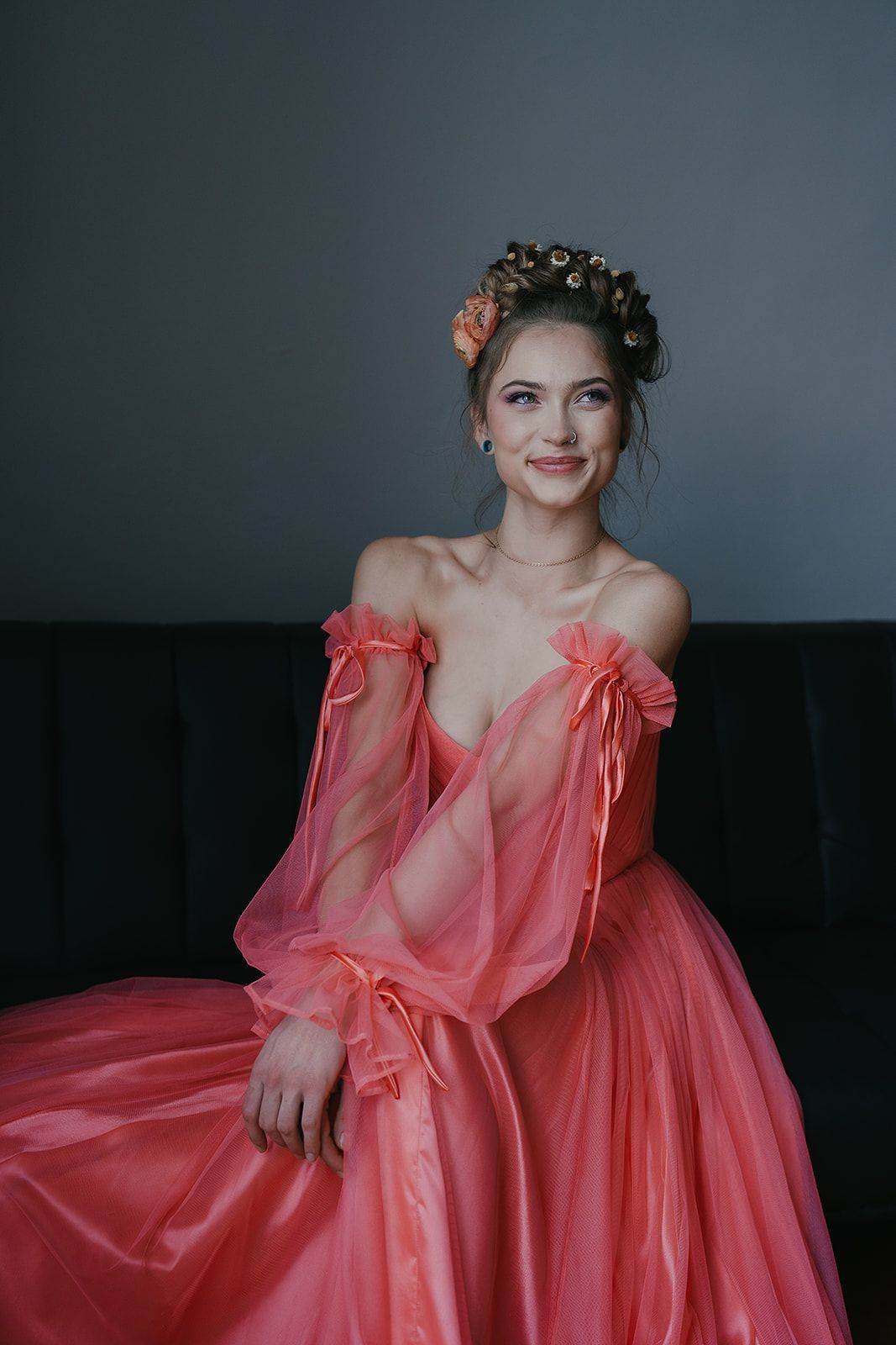 A woman in a pink dress is sitting on a couch.