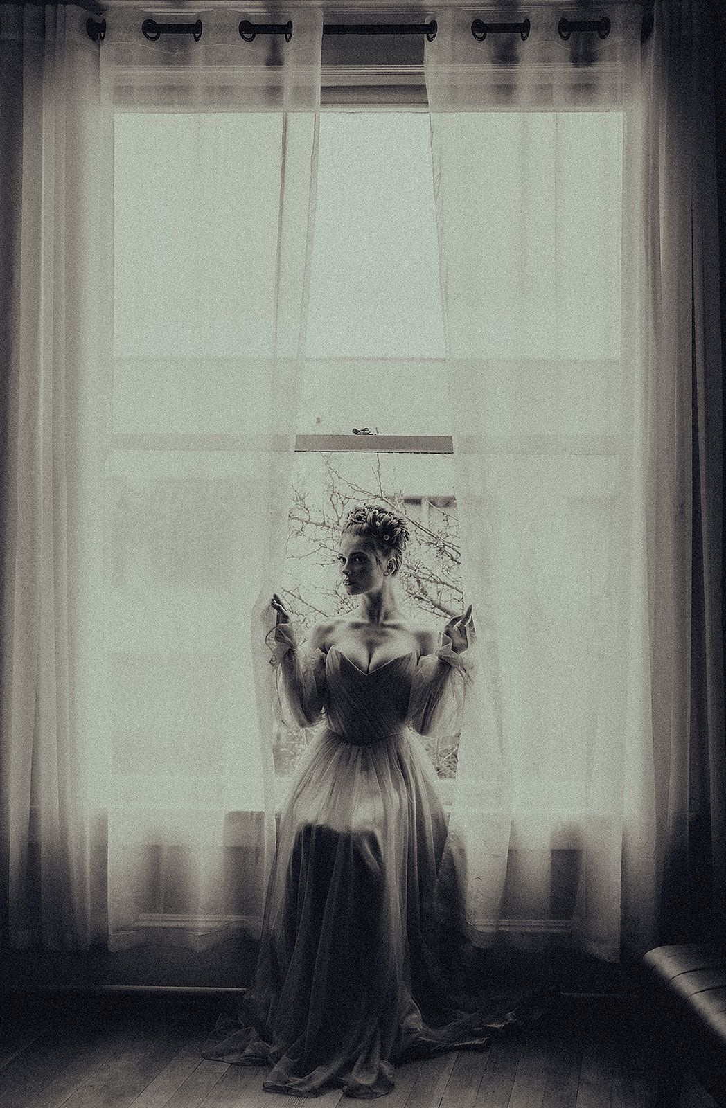 A woman in a dress is sitting in front of a window.