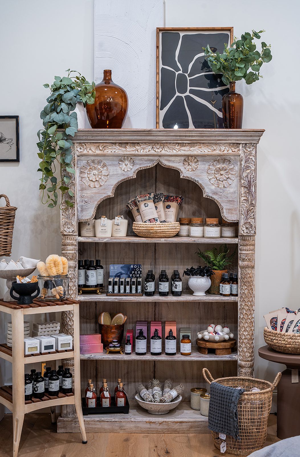 A room with a shelf filled with lots of bottles and plants.