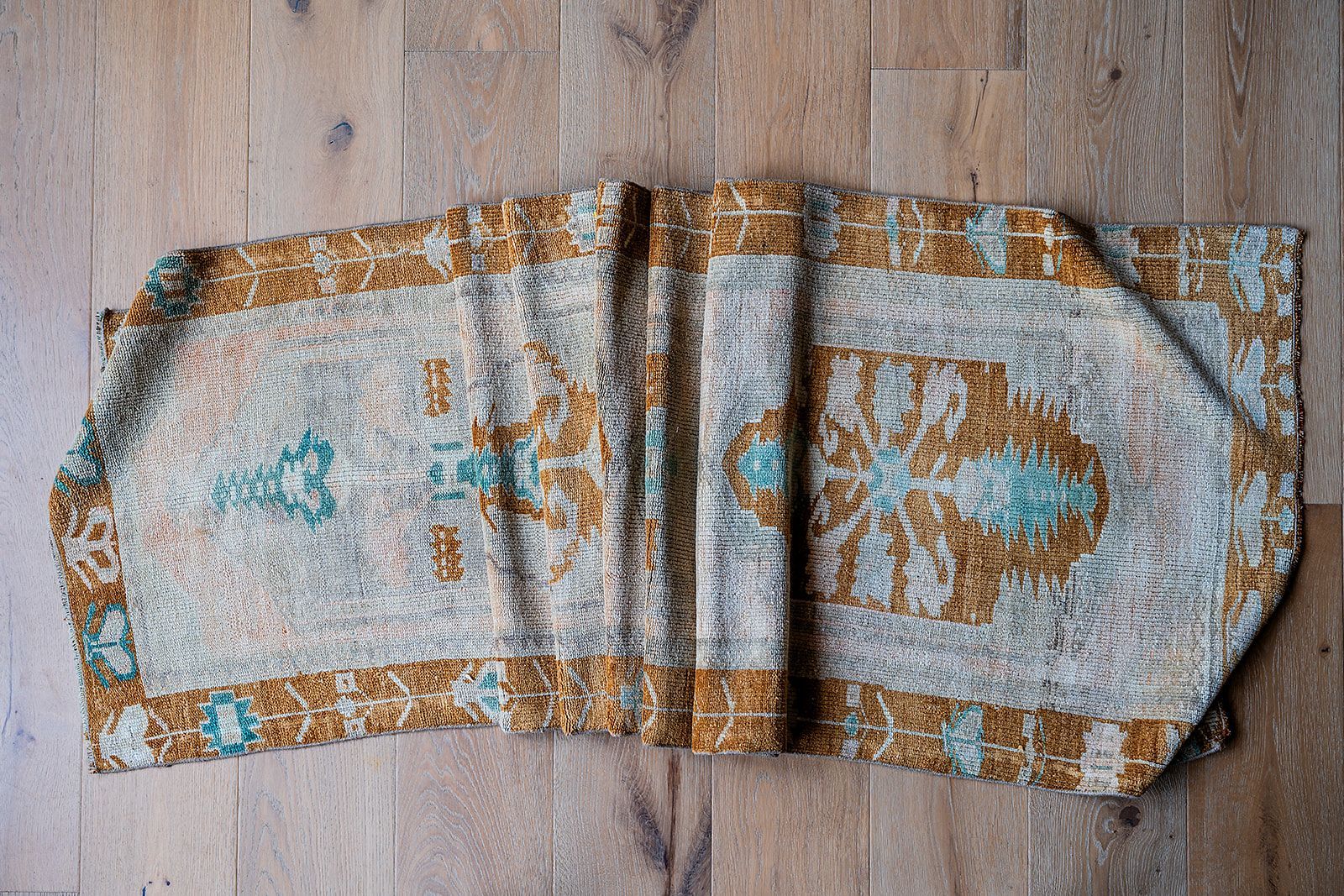 A table runner is laying on a wooden floor.