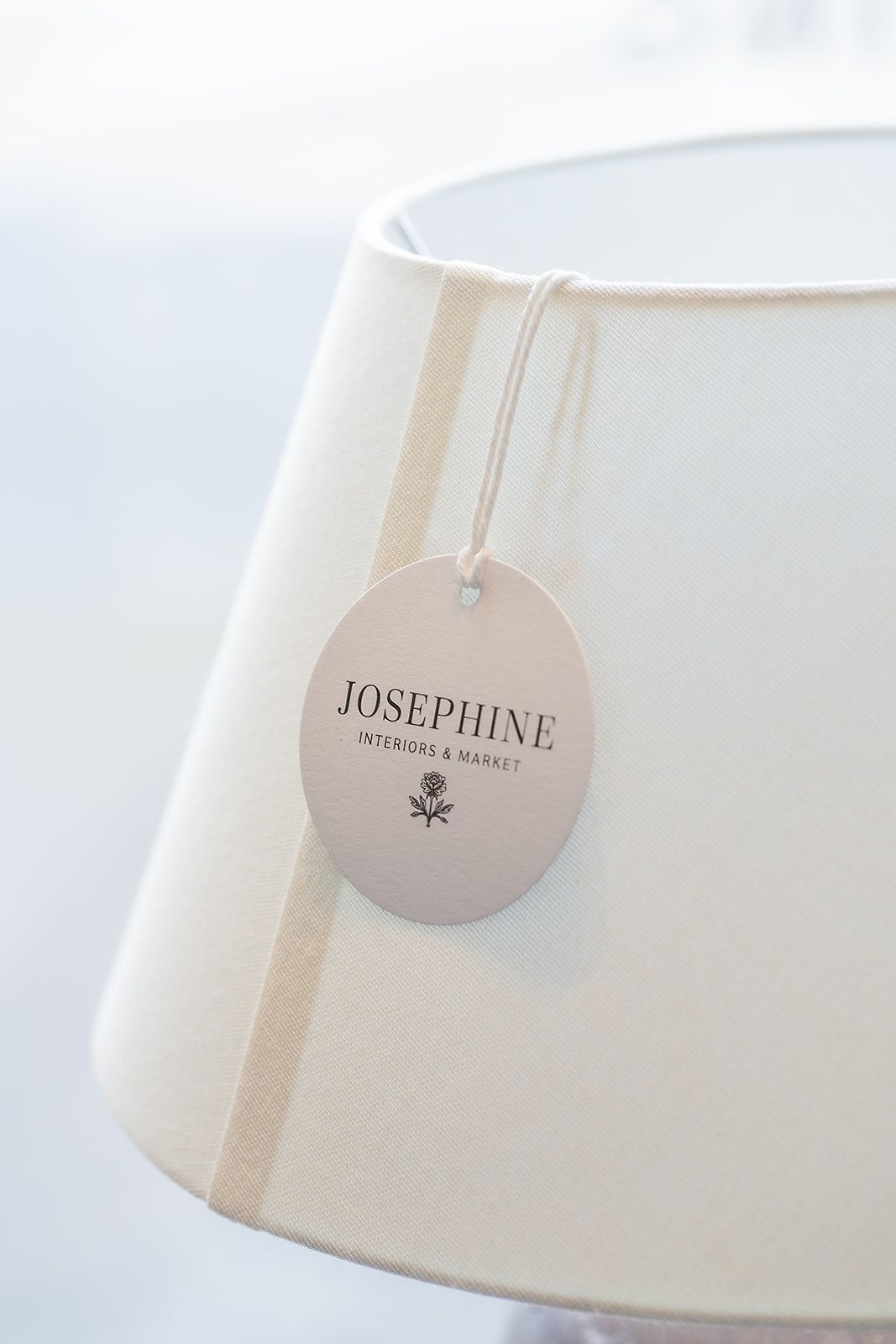 A white lamp shade with a tag attached to it.