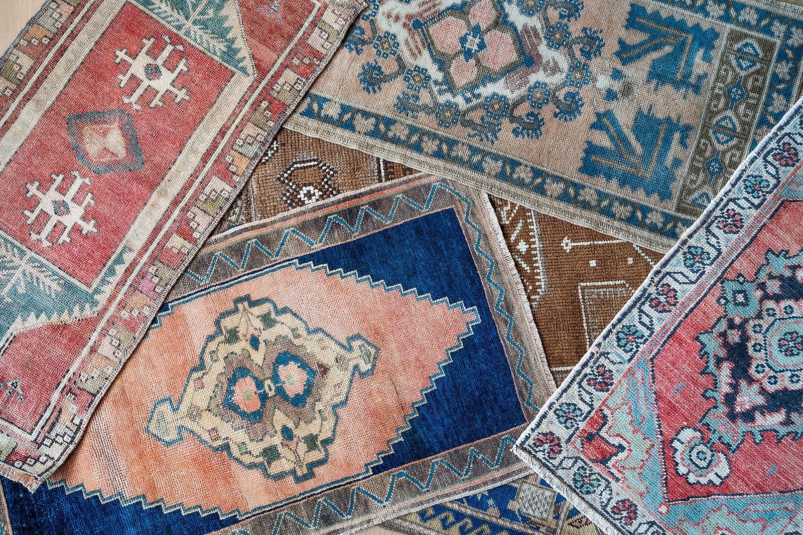 A bunch of colorful rugs are stacked on top of each other on a table.