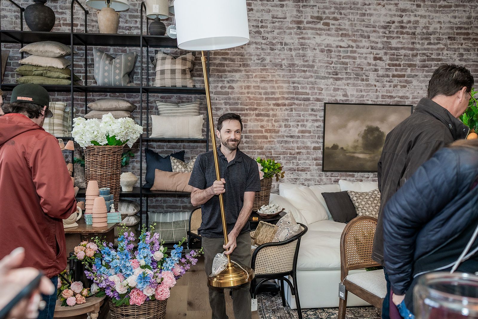 A man is standing in a living room holding a lamp.