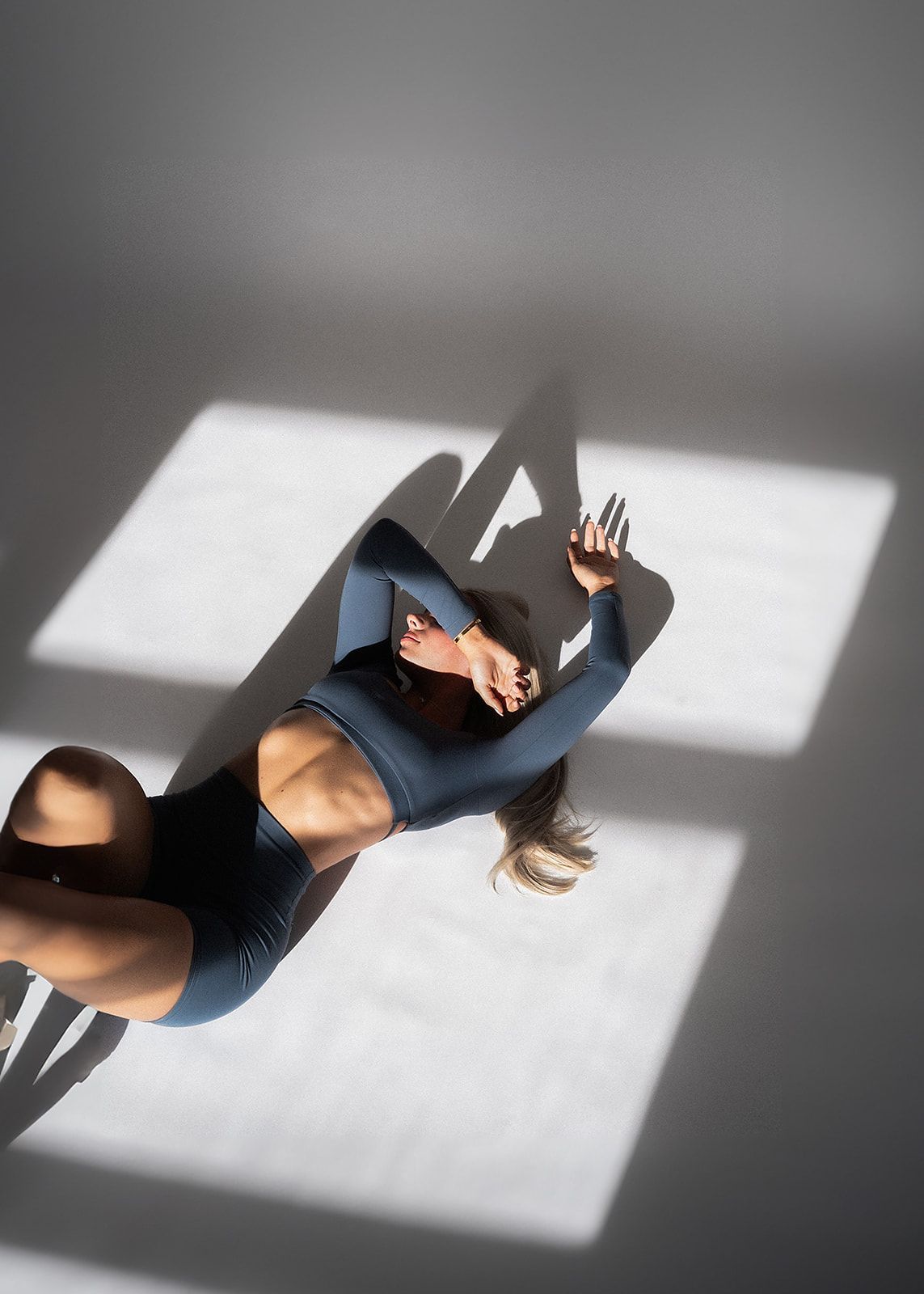 A woman is laying on the floor with her shadow cast on the floor.