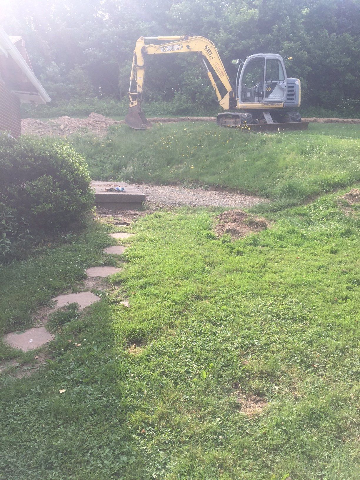 A yellow excavator is sitting in the middle of a lush green field.