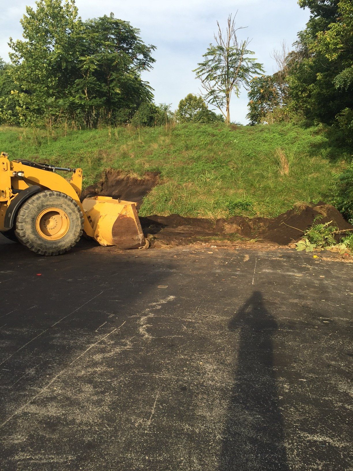 A yellow bulldozer is moving dirt in a parking lot
