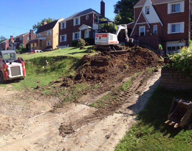 A bulldozer is moving dirt in front of a brick house