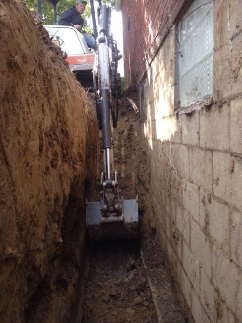 An excavator is digging a hole in the side of a building