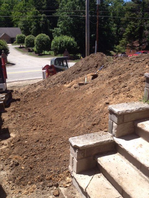 A large pile of dirt is sitting on top of a hill next to stairs