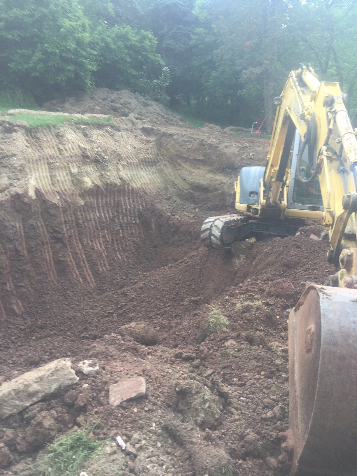 A yellow excavator is digging a hole in the dirt.