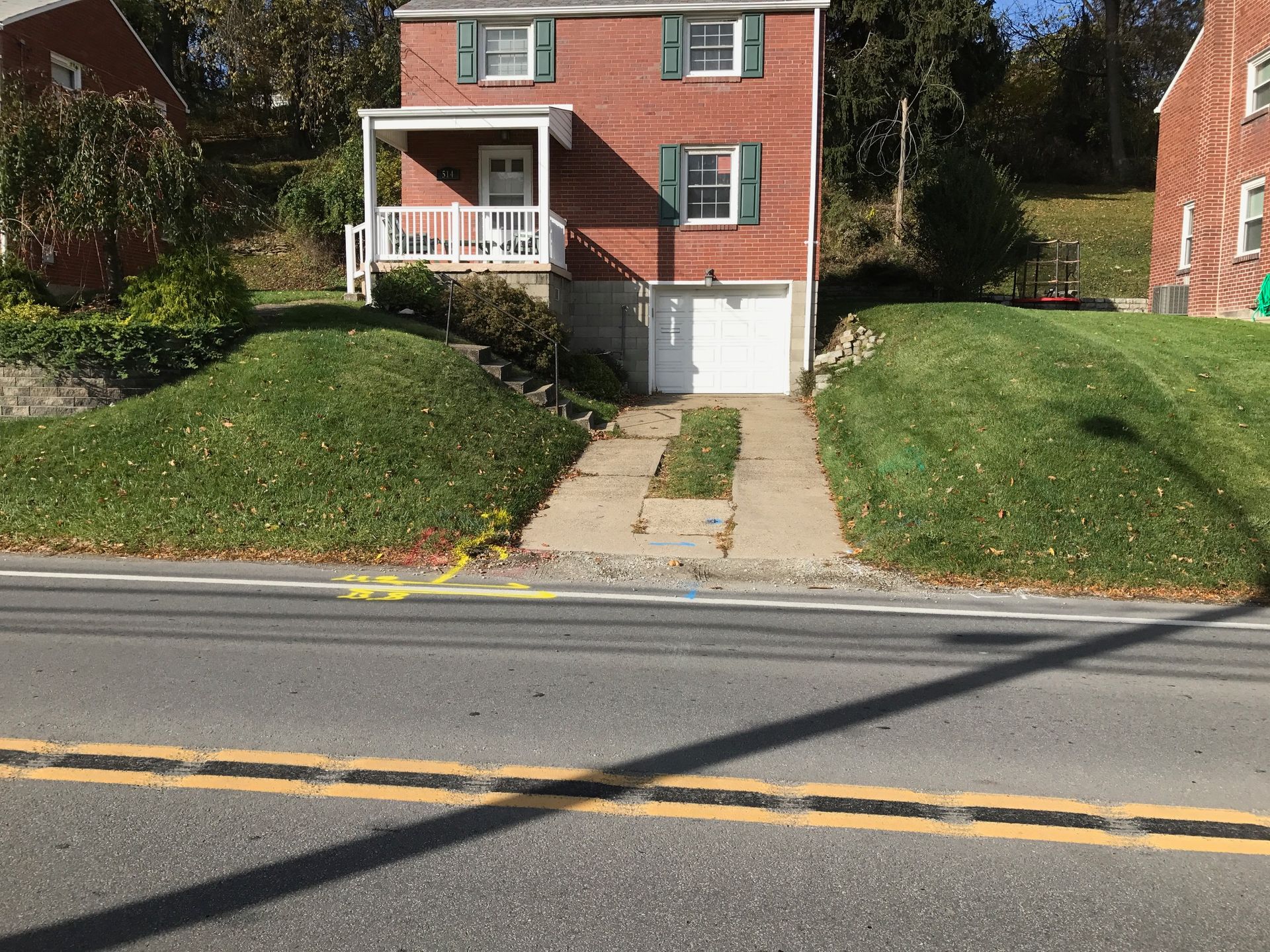 A brick house with a driveway leading to it is on the side of the road.