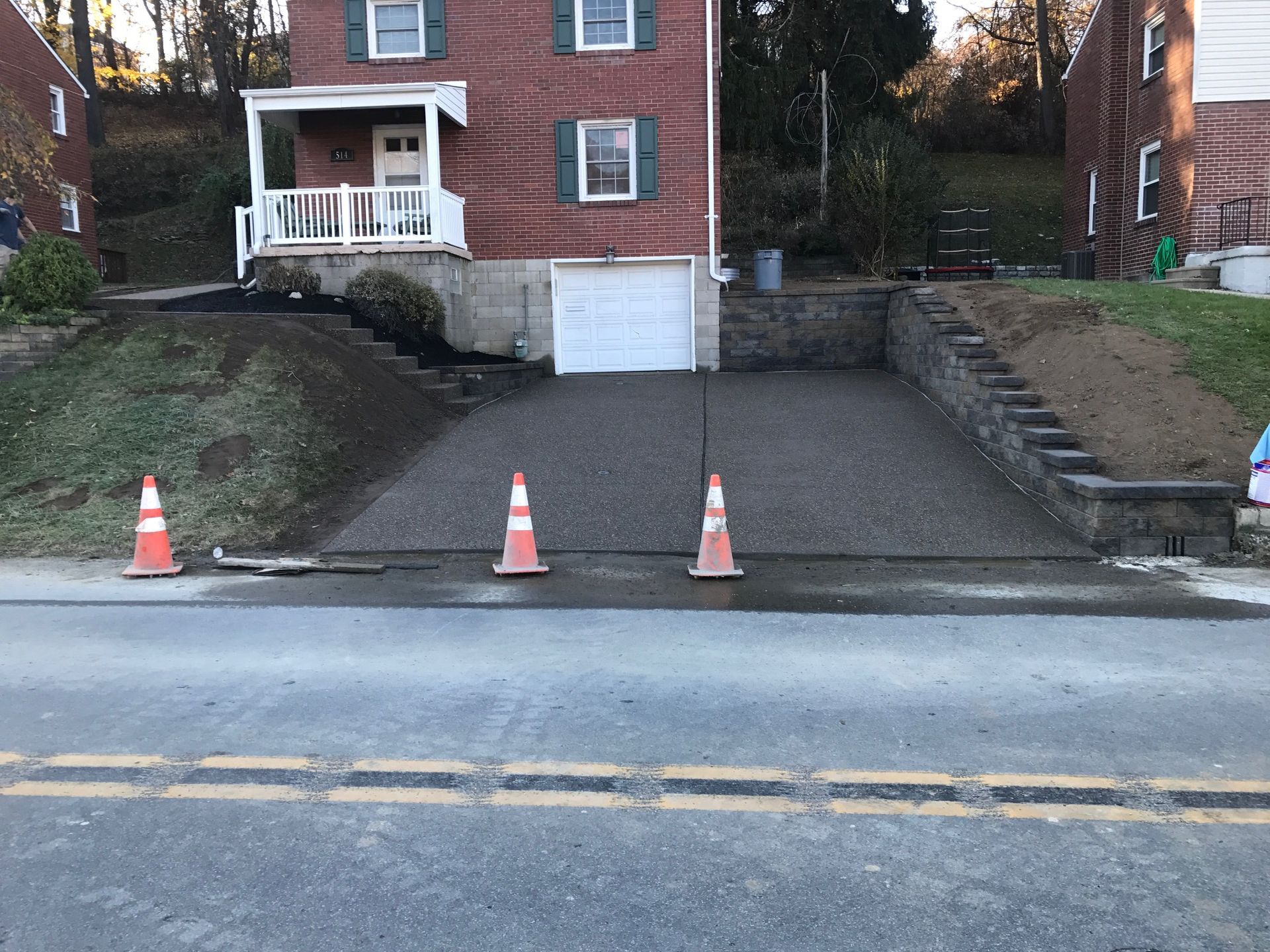 A driveway is being built in front of a brick house.