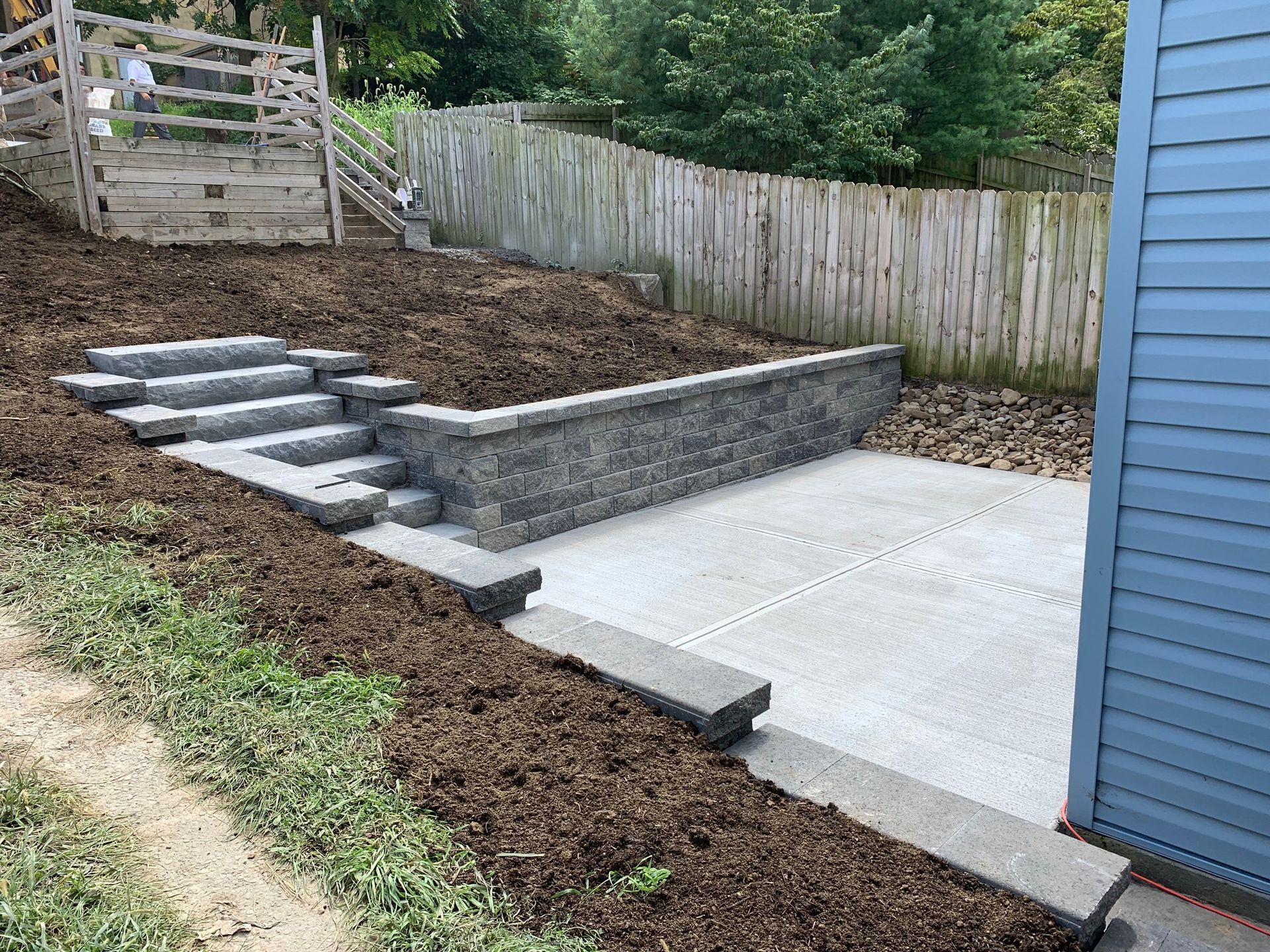 A concrete walkway with stairs leading up to a fenced in yard.